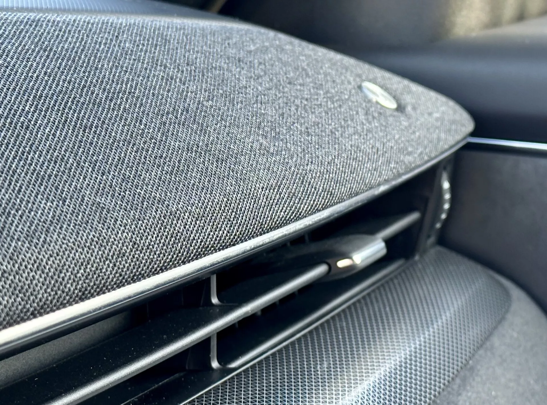 Detailný pohľad do interiéru Ford Mustang Mach-E 2020 ukazujúci časť palubnej dosky alebo dverového panelu s integrovanou mriežkou reproduktora z prémiovej tkaniny, emblémou naznačujúcou partnerstvo s výrobcom high-end audio techniky, vedľa lesklého čierneho vzduchového ventilu