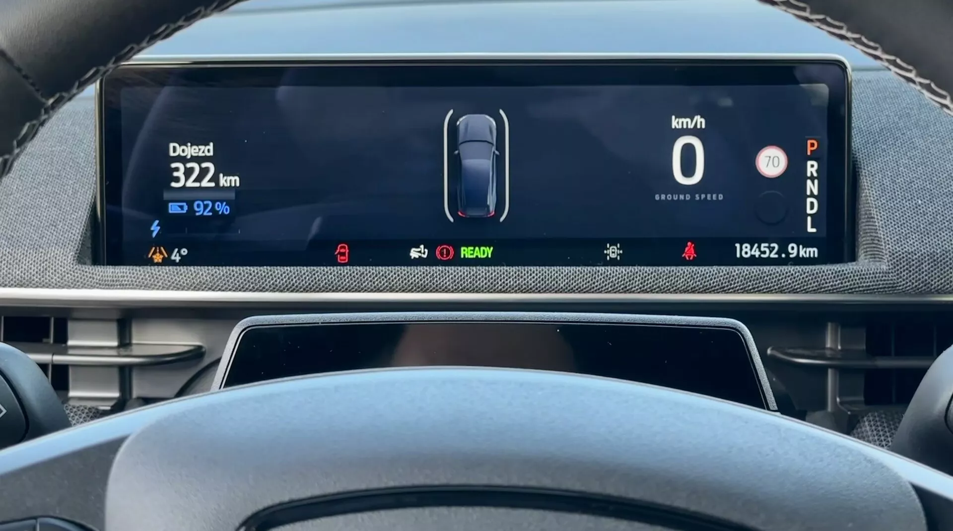 Displej digitálneho palubného panela Ford Mustang Mach-E 2020 z pohľadu vodiča zobrazujúci rýchlosť vozidla 0 km/h, zostávajúcu kapacitu batérie 92%, celkovú prejdenú vzdialenosť 18452,9 km a auto v režime parkovania, s indikátormi pre stav elektrického vozidla a pokročilými asistenčnými systémami vodiča
