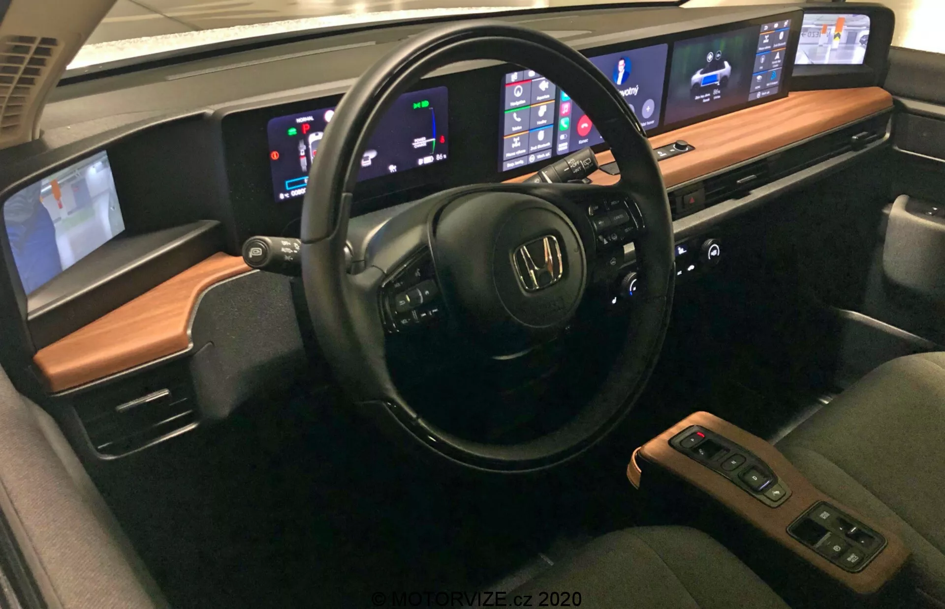 Interiér Honda e 2020 s pokročilými funkciami vrátane multifunkčného volantu s ovládaním zvuku a hlasu, digitálnej prístrojovej dosky zobrazujúcej rýchlosť a hladinu paliva, centrálne infotainment systému kompatibilného s Apple CarPlay a Android Auto, automatickej klimatizácie s duálnou zónou, pohodlných kožených sedačiek s funkciami ohrevu, stredovej konzoly s riadiacou pákou a úložným priestorom, pokročilými asistenčnými systémami vodiča, možnosťami pripojenia ako USB porty a bezdrôtové nabíjanie, prémiového zvukového systému a prispôsobiteľného ambientného osvetlenia.