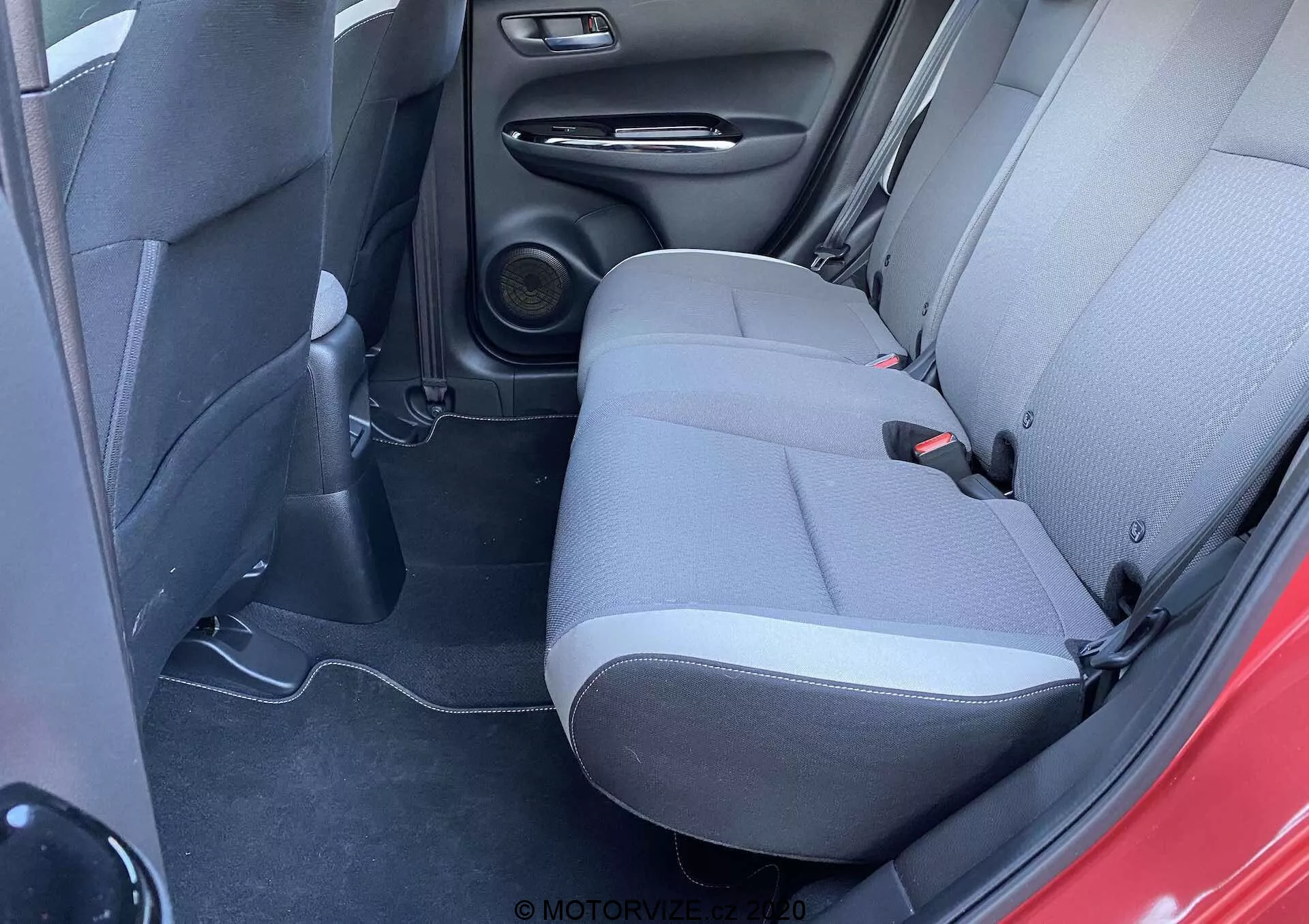 Pohľad na interiér Honda Jazz 2020 (Jazz-Crosstar) s dôrazom na zadný sedací priestor z mierne zvýšeného uhla, zdôrazňujúci dvojfarebné čalúnenie, reproduktorový systém a praktické dizajnové prvky.