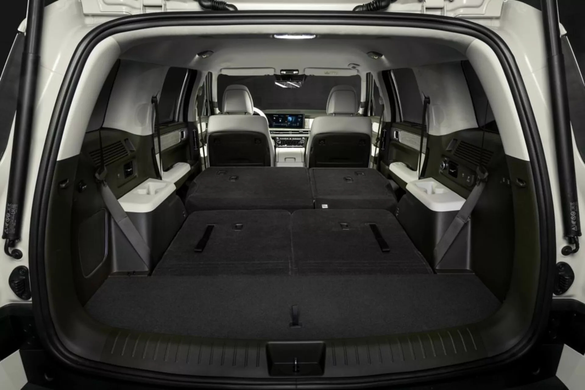 Interiér nákladného priestoru SUV Hyundai Santa Fe 2024 (5. generácia) so sklopenými zadnými sedadlami, zdôrazňujúci priestranný kufor a flexibilné usporiadanie sedačiek. Prostredná rada sedadiel je kožená, záber priamo zozadu podčiarkujúci hĺbku a užitočnosť nákladného priestoru.