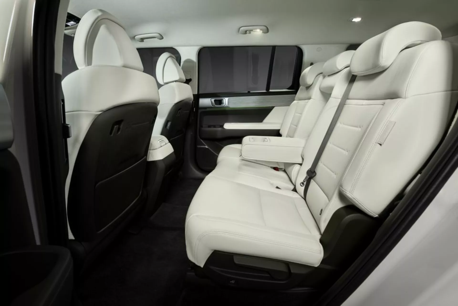 Luxusný interiér Hyundai Santa Fe 2024 (piata generácia) so zameraním na zadné sedadlá pre pasažierov. Svetlé kožené sedadlá s kontrastnými akcentmi, výsuvná stredová konzola s držiakmi na nápoje, zábavný systém pre zadné sedadlá a pokročilé ovládanie klímy a nastavenia sedadiel. Vysokokvalitné materiály a remeselné spracovanie zvyšujú pocit luxusu.