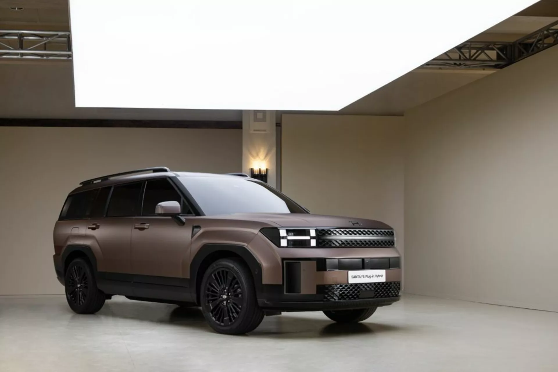 Štúdiová fotografia Hyundai Santa-Fe 2024 (5. generácie) v trojštvrťovom prednom pohľade, ktorý ukazuje jeho moderný dizajn. Vozidlo má prepracovanú prednú masku s elegantnými LED svetlometmi a predný nárazník s integrovanými senzormi. Bočný profil zvýrazňuje veľké zliatinové kolesá, strešné nosiče, tónované okná a bočný schodík. Matný lak je zvýraznený kontrolovaným ateliérovým osvetlením, ktoré zdôrazňuje luxusný a robustný vzhľad SUV na minimalistickom pozadí.