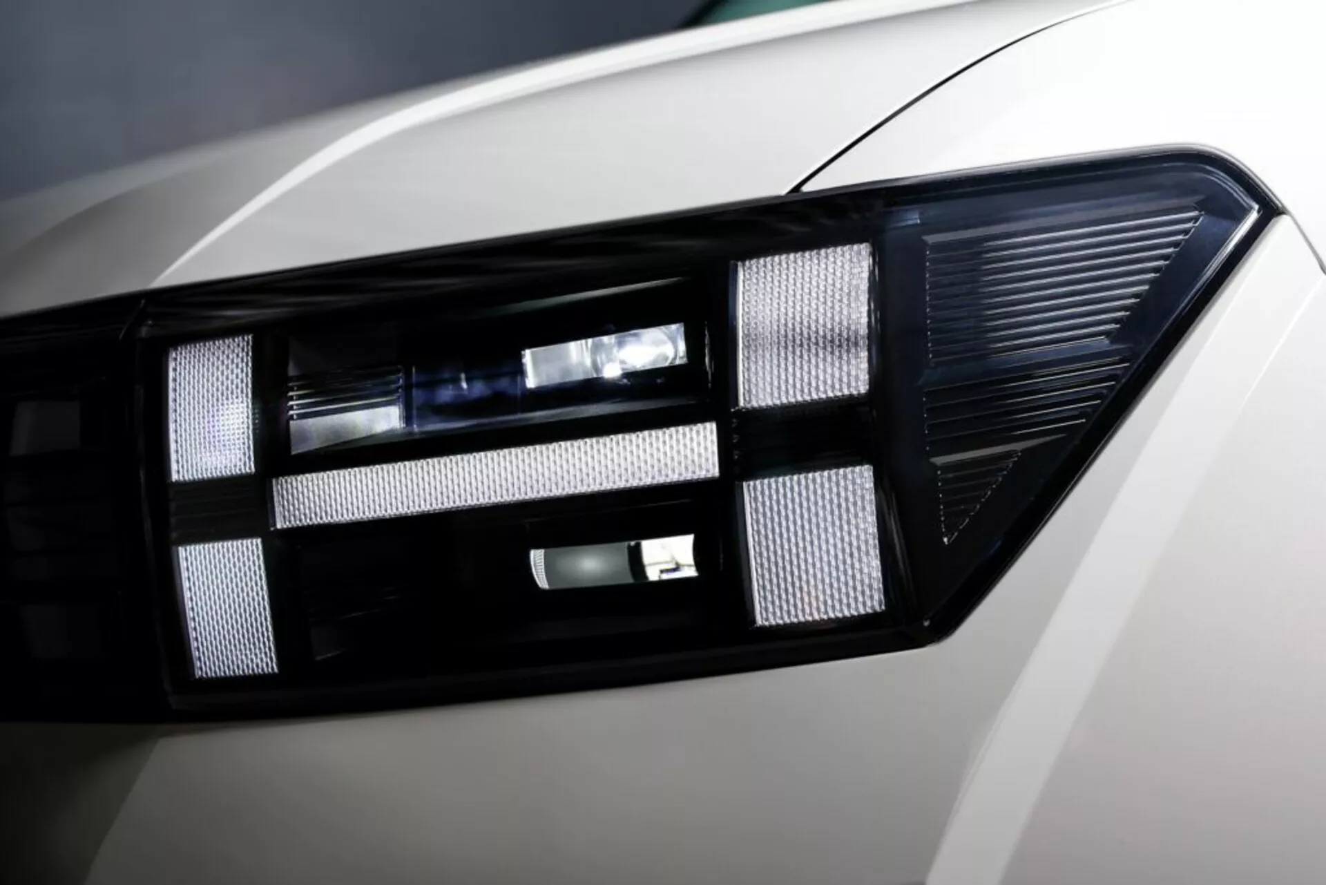 Detailný záber na moderný svetelný klastr modelu Hyundai Santa Fe 2024 (5. generácia) s pokročilou LED/HID technológiou osvetlenia, elegantným dizajnom, projektorovou šošovkou a lesklým povrchom karosérie.
