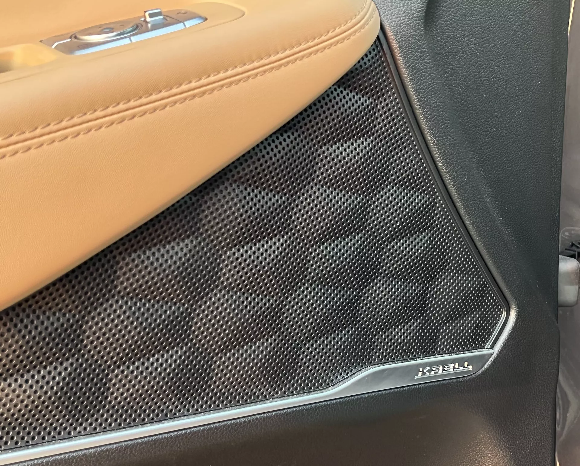 Detailný pohľad na interiérový panel dverí Hyundai Santa Fe 2020, zameraný na prechod medzi béžovým koženým čalúnením s kontrastným šitím a mriežkou reproduktora Bowers & Wilkins. Textúrovaný, perforovaný kryt reproduktora s chrómovaným emblémom Bowers & Wilkins zdôrazňuje prémiový audiosystém a luxusné materiály vozidla.