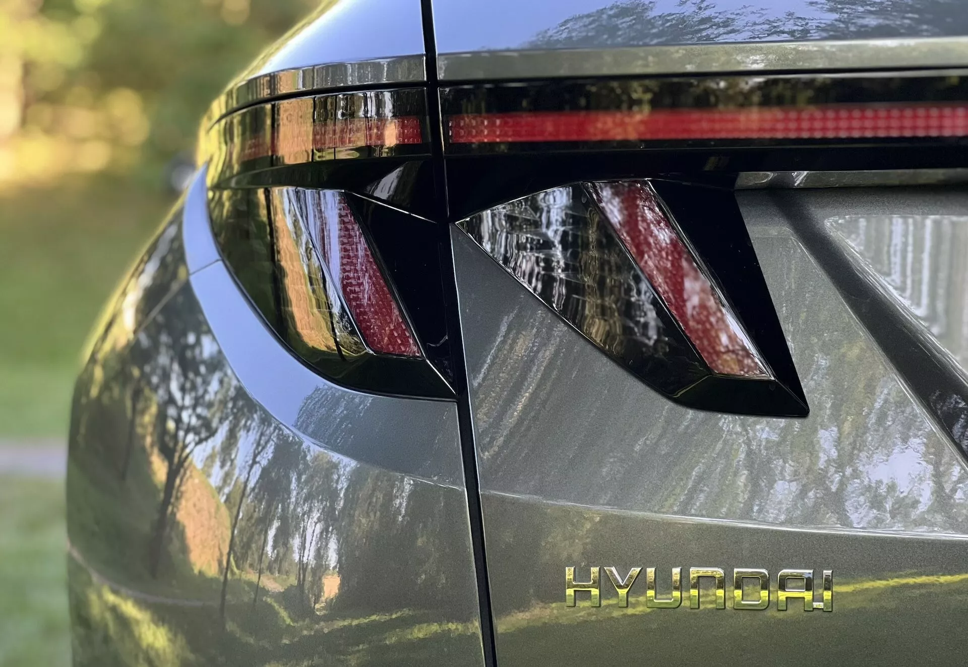 Detailný pohľad na zadnú časť Hyundai Tucson 2020, predstavujúci uhlové LED zadné svetlá, značenie HYUNDAI, integrovaný zadný spojler s brzdovým svetlom a lesklý kovový povrch