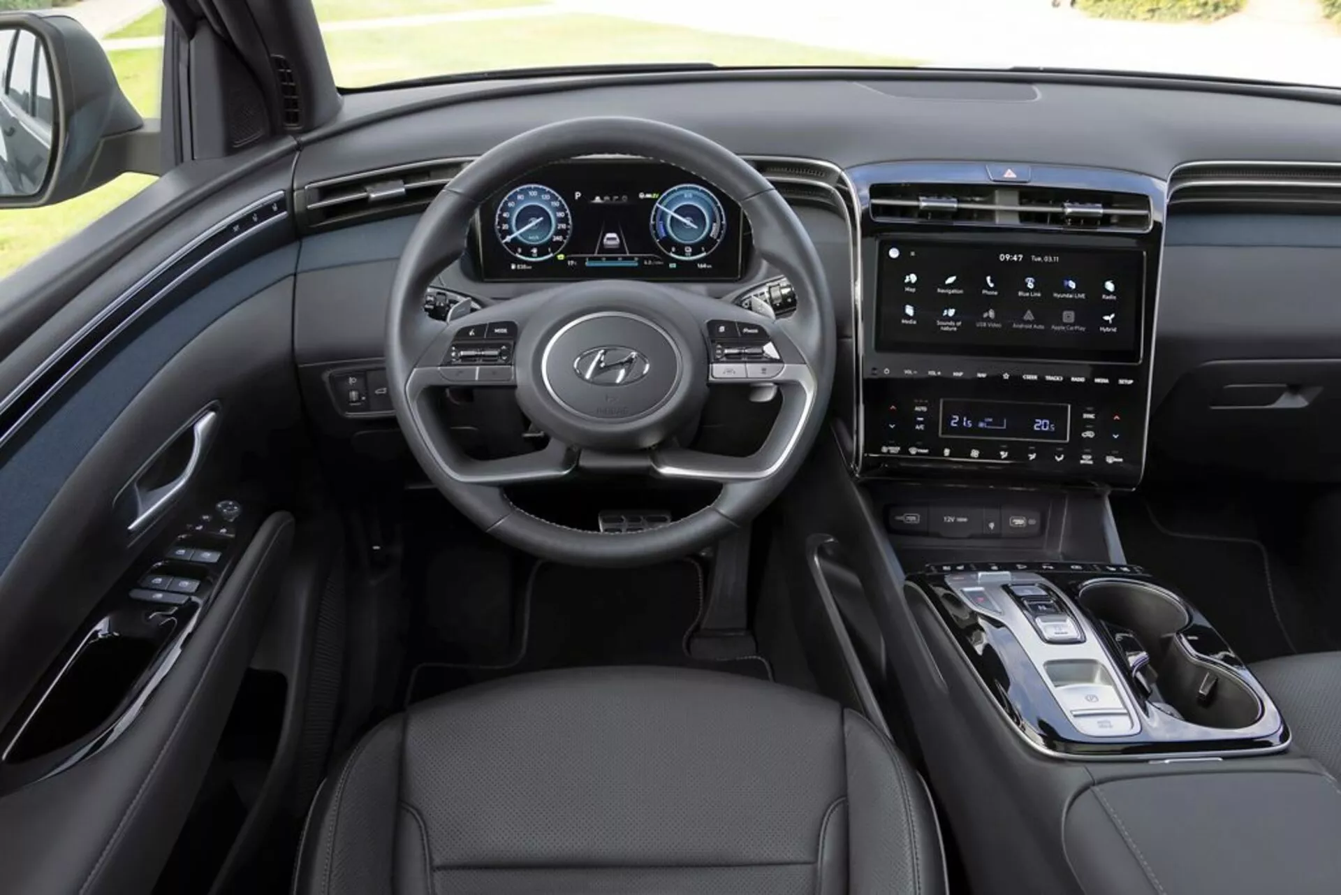 Interiér Hyundai Tucson 2020 z pohľadu vodiča, zdôraznenie palubnej dosky, multifunkčného volantu s logom Hyundai, plne digitálneho prístrojového panelu, vertikálneho dotykového informačného systému, minimalistických ovládacích prvkov na stredovej konzole, elektronického výberu prevodov, čalúnenie z kože a sofistikovaného monochromatického farebného schémy