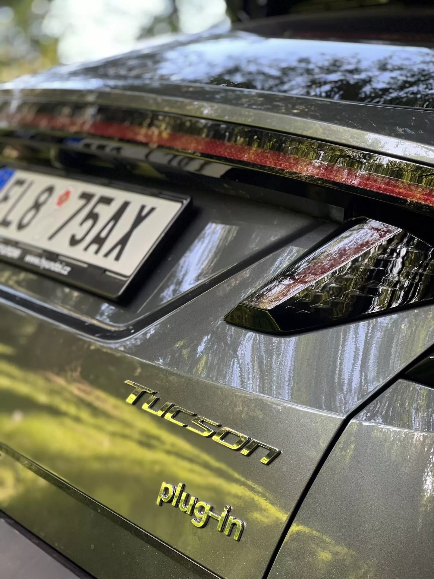 Detailný pohľad na zadnú časť Hyundai Tucson 2020 plug-in hybrid, vrátane veka batožinového priestoru, zadného svetelného zoskupenia s LED svetlami, tmavý lesklý povrch a detaily naznačujúce parkovanie v exteriéri