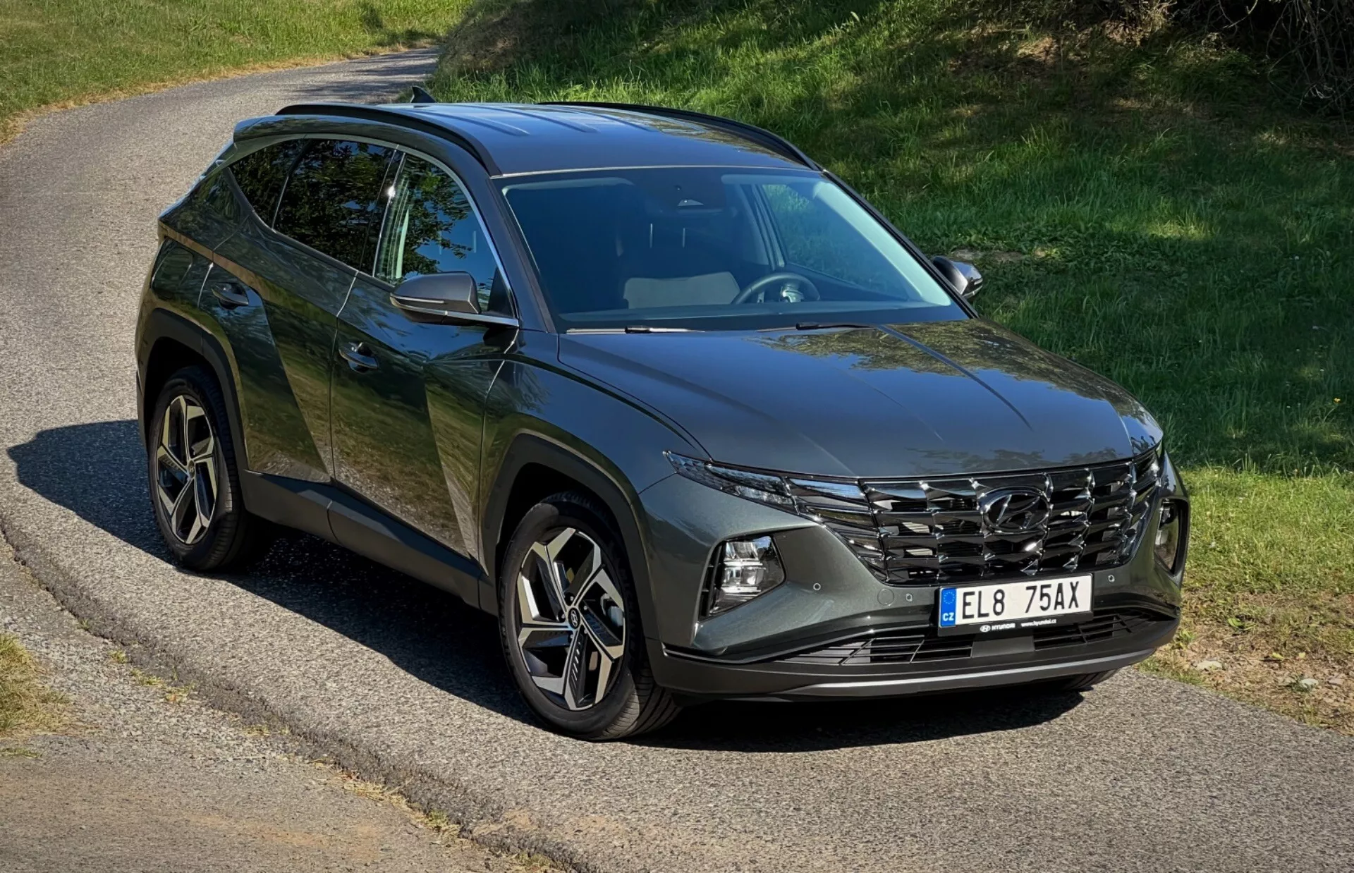 SUV Hyundai Tucson 2020 zaparkované na opustenej ceste predvádzajúce svoju prednú mriežku, LED svetlomety, zliatinové kolesá a línie karosérie pod prírodným slnečným svetlom