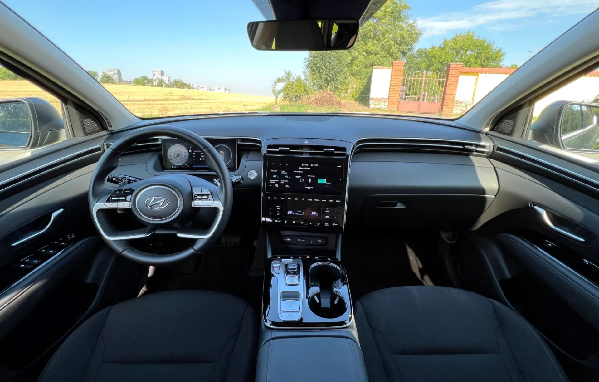 Interiér Hyundai Tucson 2020 zobrazujúci predné sedadlá, volant s logom výrobcu a ovládacími tlačidlami, digitálny prístrojový panel, vertikálny dotykový infotainment systém na stredovej konzole, automatickú radicu páku a dizajn palubnej dosky vo dvojfarebnom prevedení z pohľadu vodiča