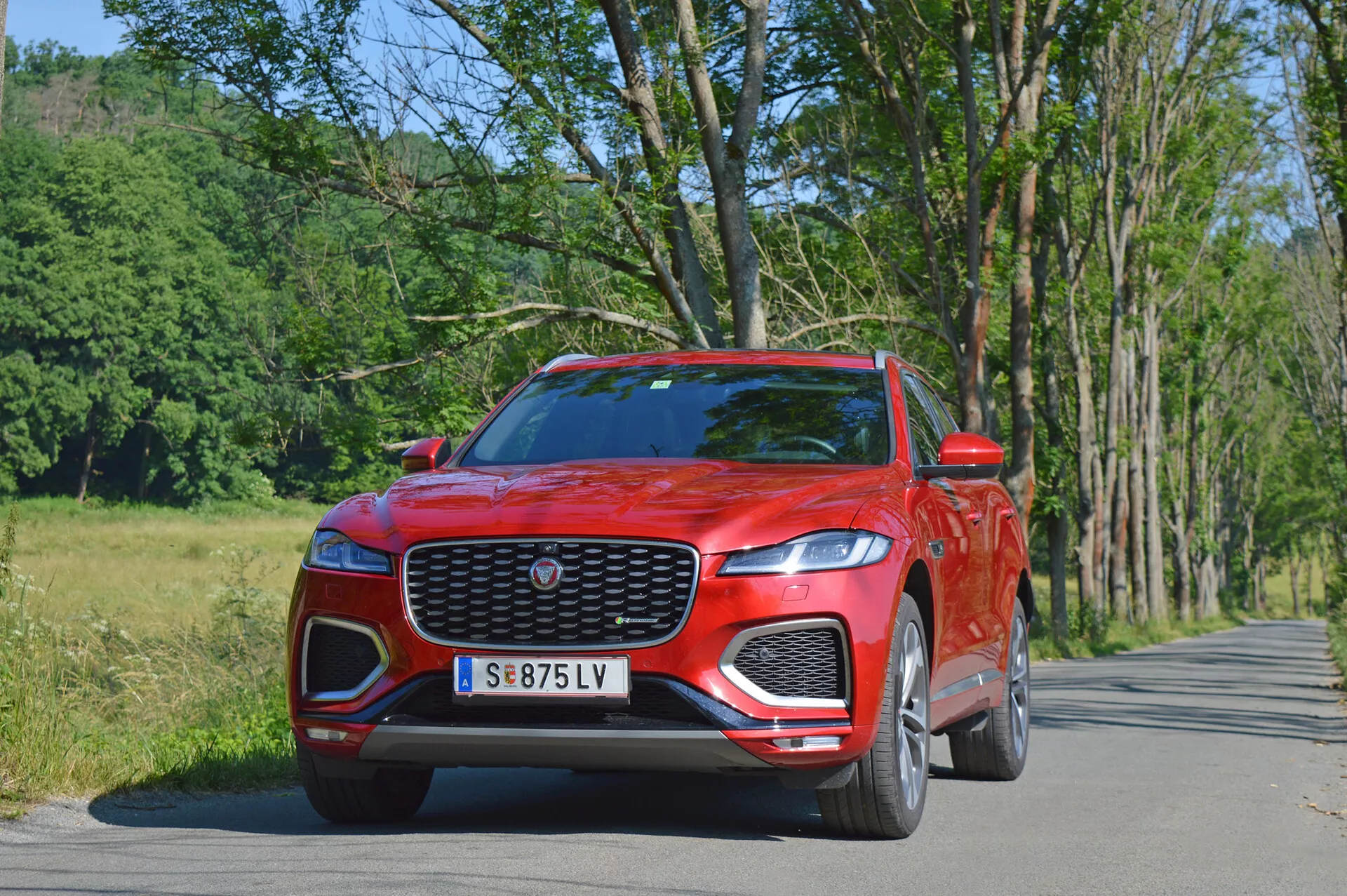 Luxusné SUV Jaguar F-Pace 2021 v štýlovej striebornej farbe, zachytené počas dynamickej jazdy v meste, zdôrazňujúc výraznú prednú masku, LED svetlomety a športové zliatinové kolesá.