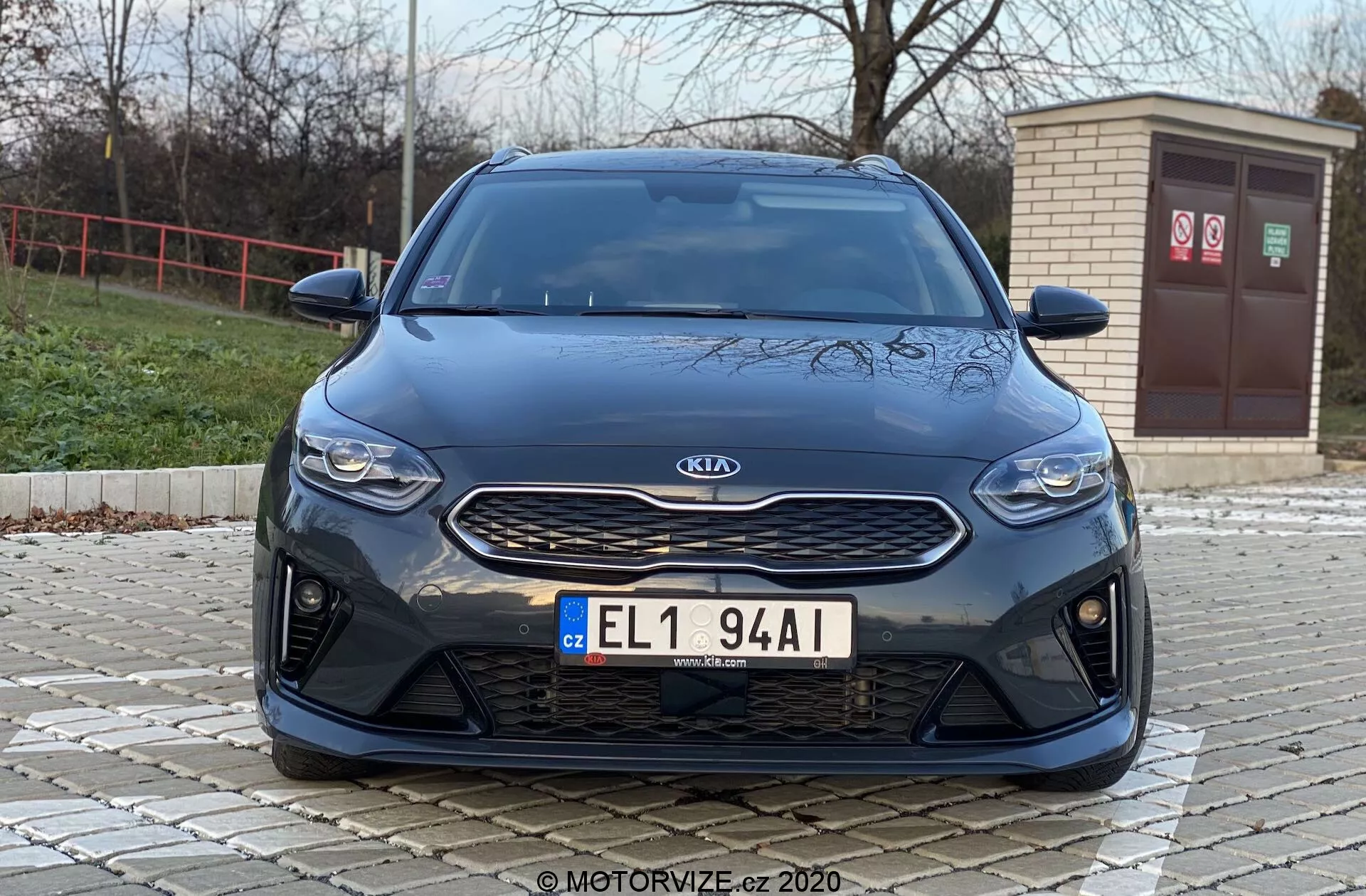 Predný pohľad na auto Kia Ceed 2018 z nízkeho uhla, ukazujúci čelné prvky ako mriežka, svetlomety a nárazník s modernou estetikou. Obrázok zvýrazňuje strieborný emblém Kia na textúrovanej čiernej mriežke, štíhle horizontálne svetlomety a predný nárazník s veľkými nasávacími otvormi, naznačujúcimi športové výkonnostné prvky alebo pokročilé chladenie prúdom vzduchu.