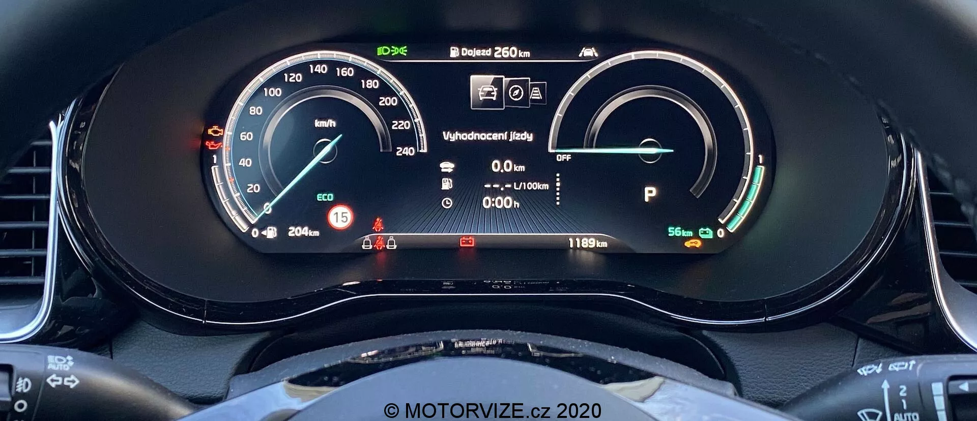 Detailný pohľad na digitálny prístrojový panel Kia Ceed 2018 z pohľadu vodiča. Displej zahŕňa rýchlomer s fyzickou ručičkou a digitálnym zobrazením, ukazujúcim 15 km/h. Vpravo sa nachádza merač výkonu/batérie, čo indikuje plne nabitú batériu s dojazdom 481 km. Ďalšie prvky zahŕňajú stavový displej pripravený, informačný displej vodiča s varovnými svetlami, vonkajšiu teplotu 20,5°C a vozidlo v režime Park. Viditeľný je aj horný oblúk volantu s športovým, plochým spodným dizajnom.