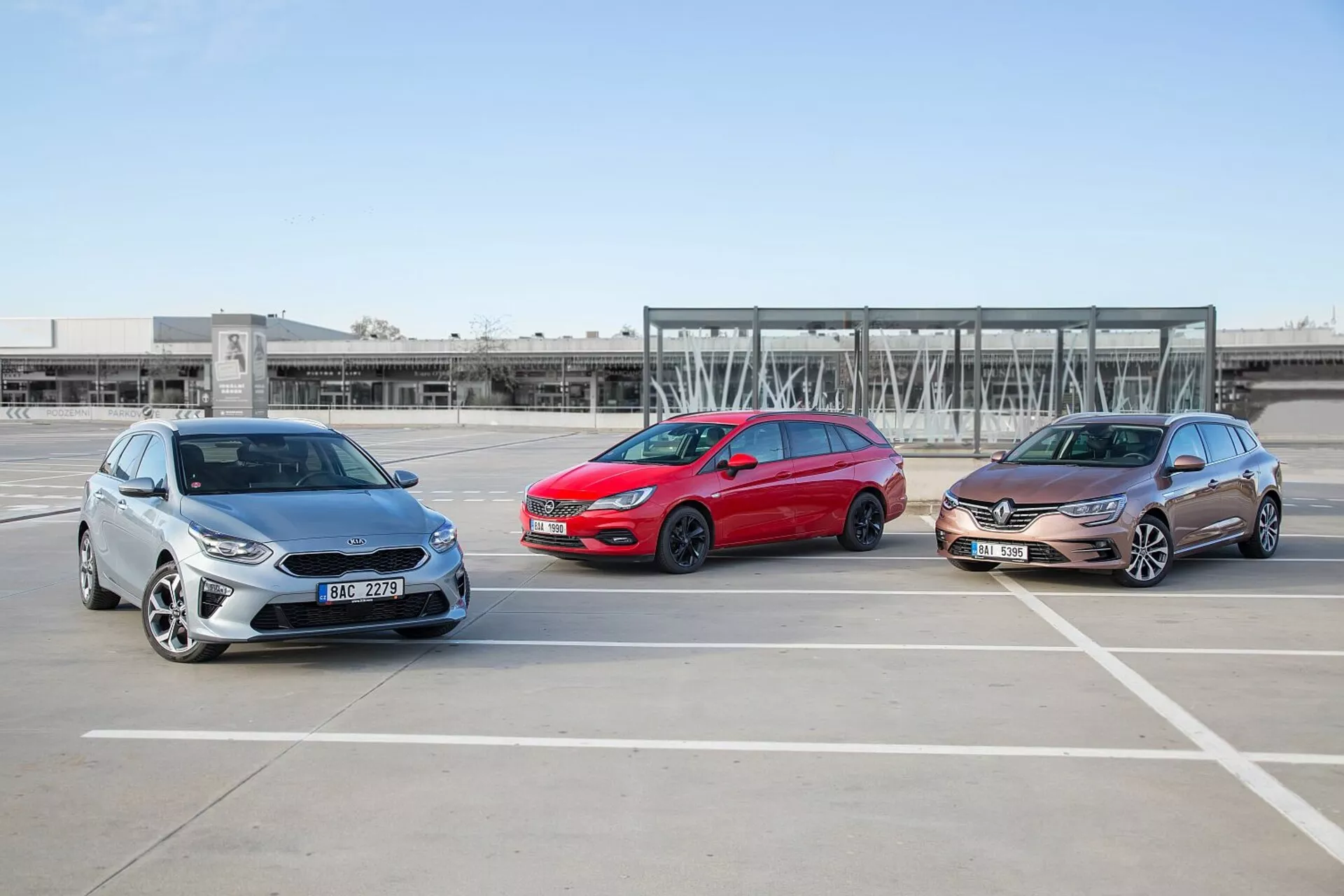 Tri modely Kia Ceed 2009, rozmiestnené v šachovnicovej formácii na prázdnom parkovisku, predvádzajúce svoje predné a bočné profily za jasných poveternostných podmienok
