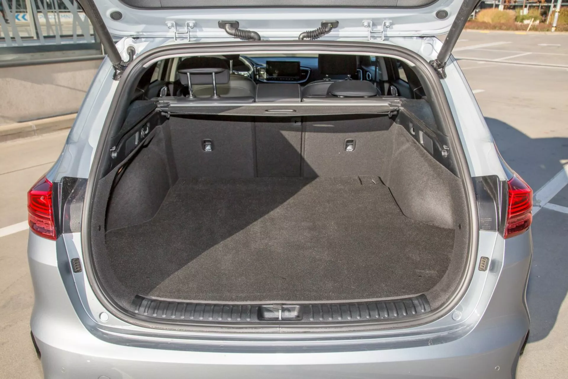 Zadný batožinový priestor hatchbacku Kia Cee'd 2009 s otvoreným vekom, ukazujúci priestranný čistý nákladný priestor, koberček, zasúvateľný kryt a potenciálne vnútorné osvetlenie