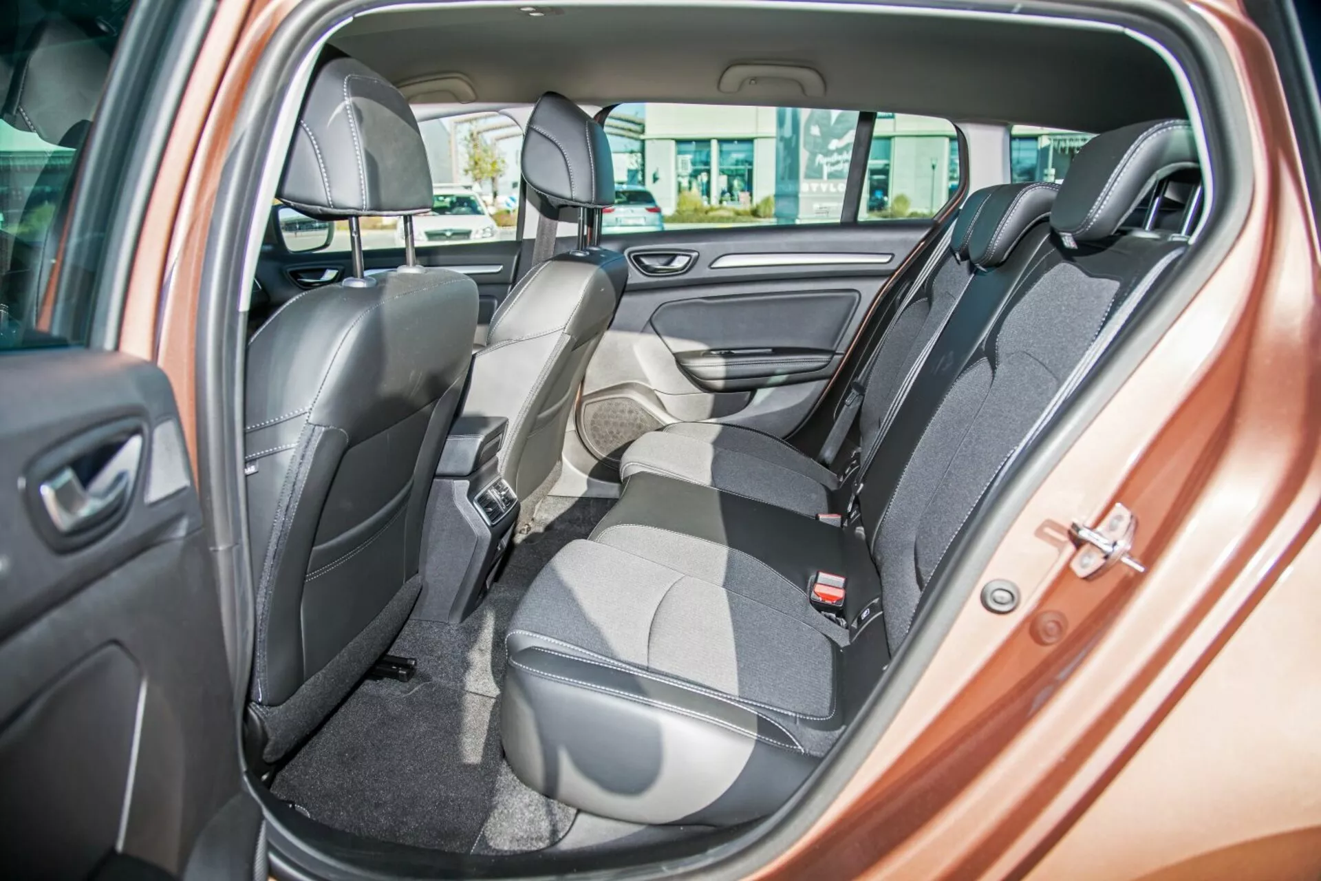 Interiér Kia Ceed 2009 ukazujúci dvojfarebné zadné sedadlo s jedným sedadlom sklopeným dopredu pre náklad, bezpečnostné pásy, opierky hlavy, ovládanie elektrických okien a reproduktor na dverách, zdôrazňujúci flexibilné usporiadanie sedadiel a luxusný dizajn