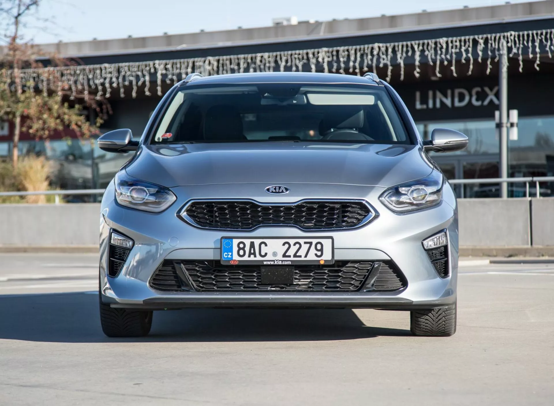 Model Kia Ceed 2009 v metalickej striebornej farbe, pohľad zpredu a zo strany pri jasnom dennom svetle, predvádzajúci zliatinové kolesá a aerodynamický dizajn
