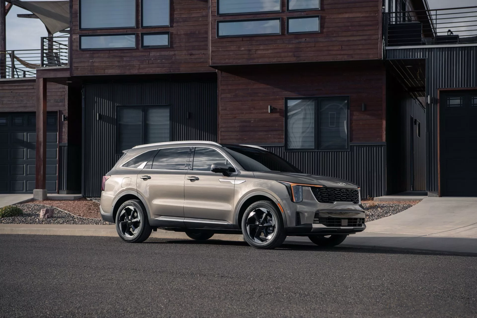 Model Kia Sorento MQ4 facelift 2024 zaparkovaný na mestskej ulici, zobrazený z uhla tri štvrtiny spredu, čo zdôrazňuje jeho moderný dizajn s výraznou prednou mriežkou, LED svetlometmi, kolesami z ľahkých zliatin s viacerými paprskami a štýlovou dvojfarebnou schémou lakovania na pozadí súčasných rezidencií.