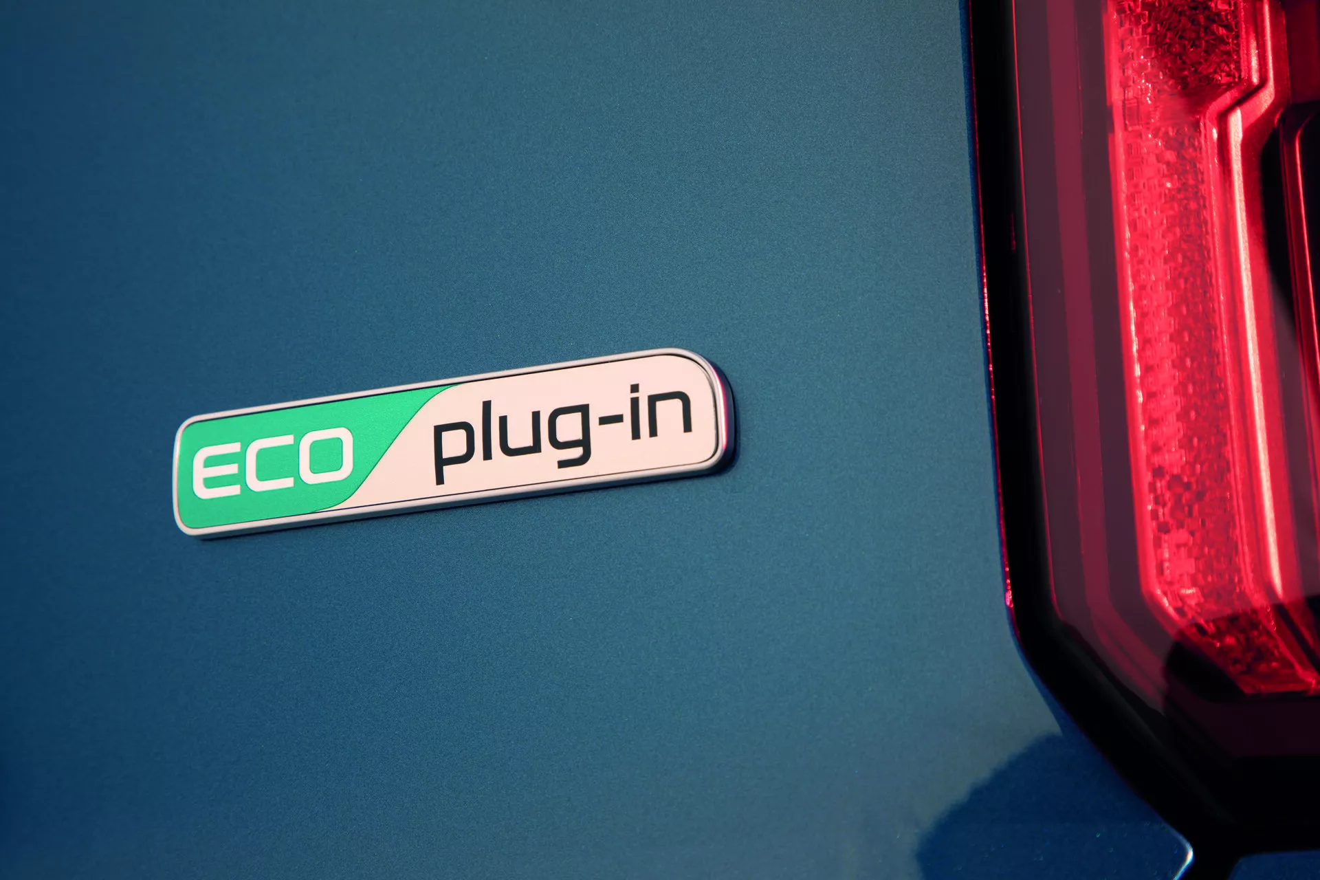 Detailný pohľad na odznak ECO plug-in Kia Sorento 2020 (MQ4), ktorý zdôrazňuje hybridnú technológiu na modrej karosérii s náznakom moderného LED zadného svetla