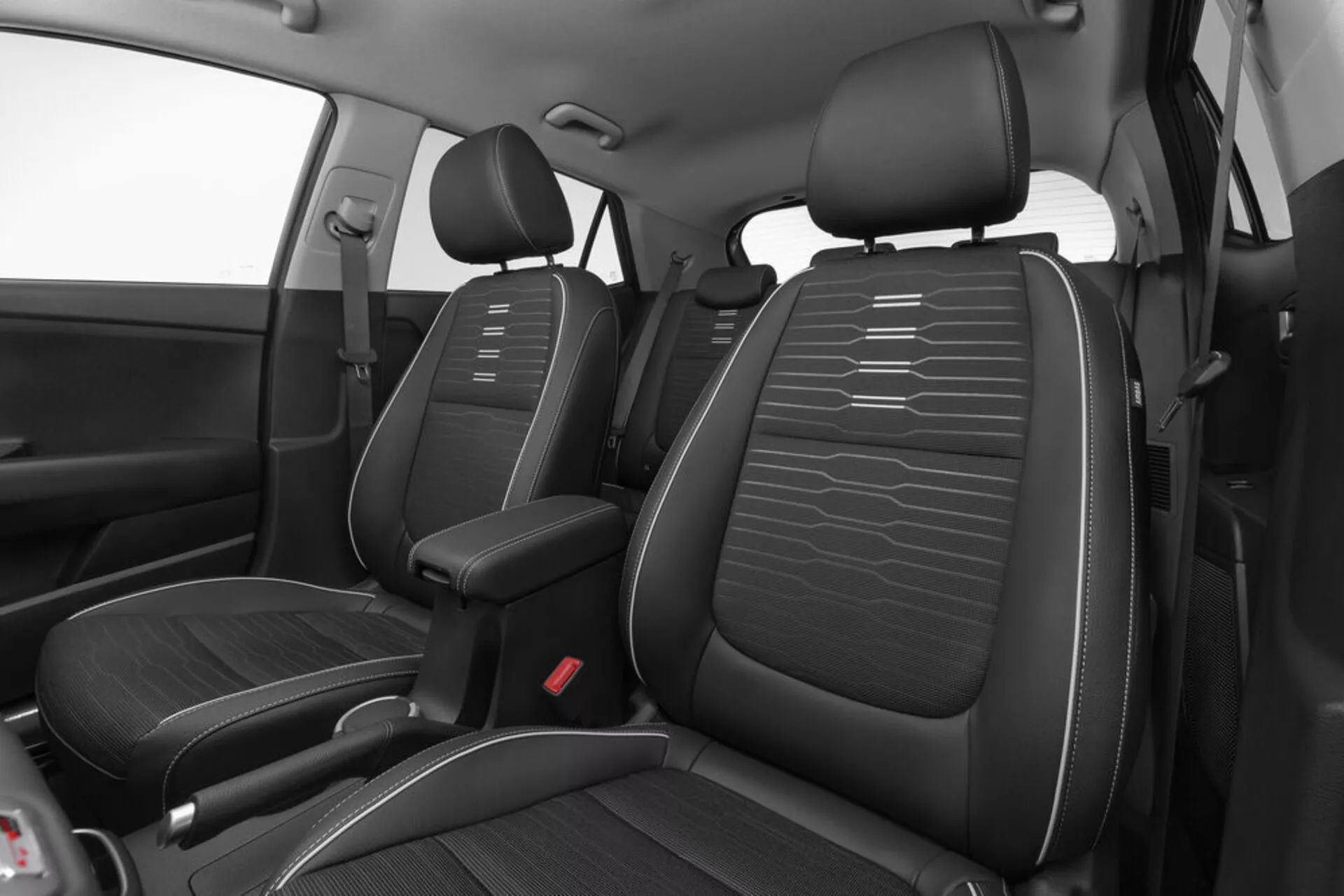 Vysoký uhol pohľadu na predný interiér Kia Stonic 2017 s čiernymi sedačkami z umelej kože a horizontálnym šitím, stredovou konzolou a červenými bodcami bezpečnostných pásov s dôrazom na dizajn a rozloženie