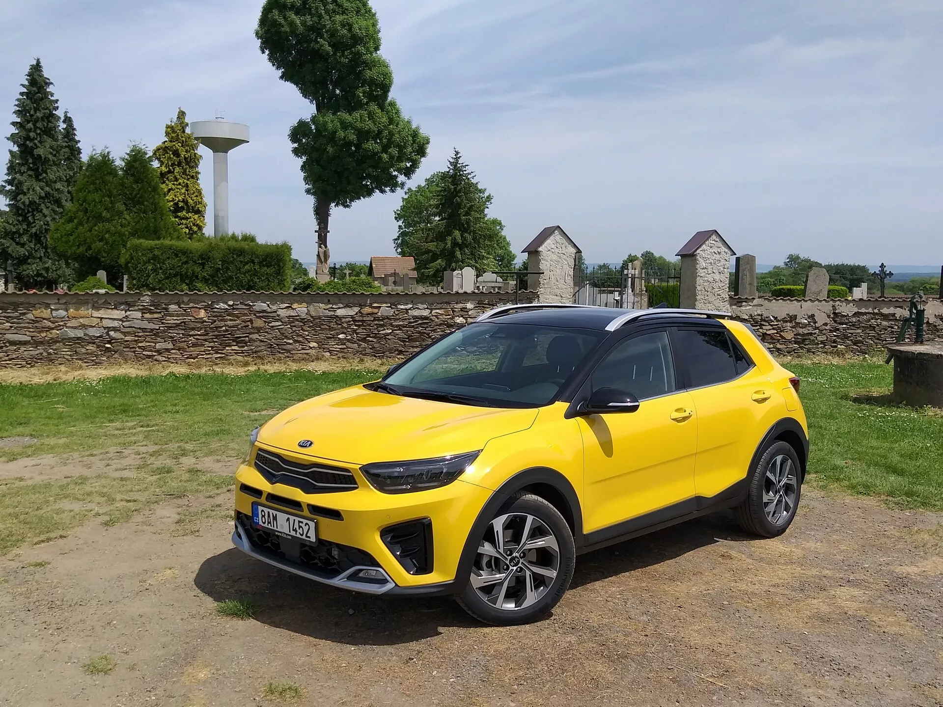 Kia Stonic 2017 vo svetložltej farbe, prezentujúca svoju prednú mriežku, LED svetlomety, športový predný nárazník a štýlový bočný profil s viacerými hovorčivými zliatinovými kolesami a strešnými nosičmi, čo zdôrazňuje estetiku kompaktného crossoveru a pokročilé dizajnové prvky vozidla.