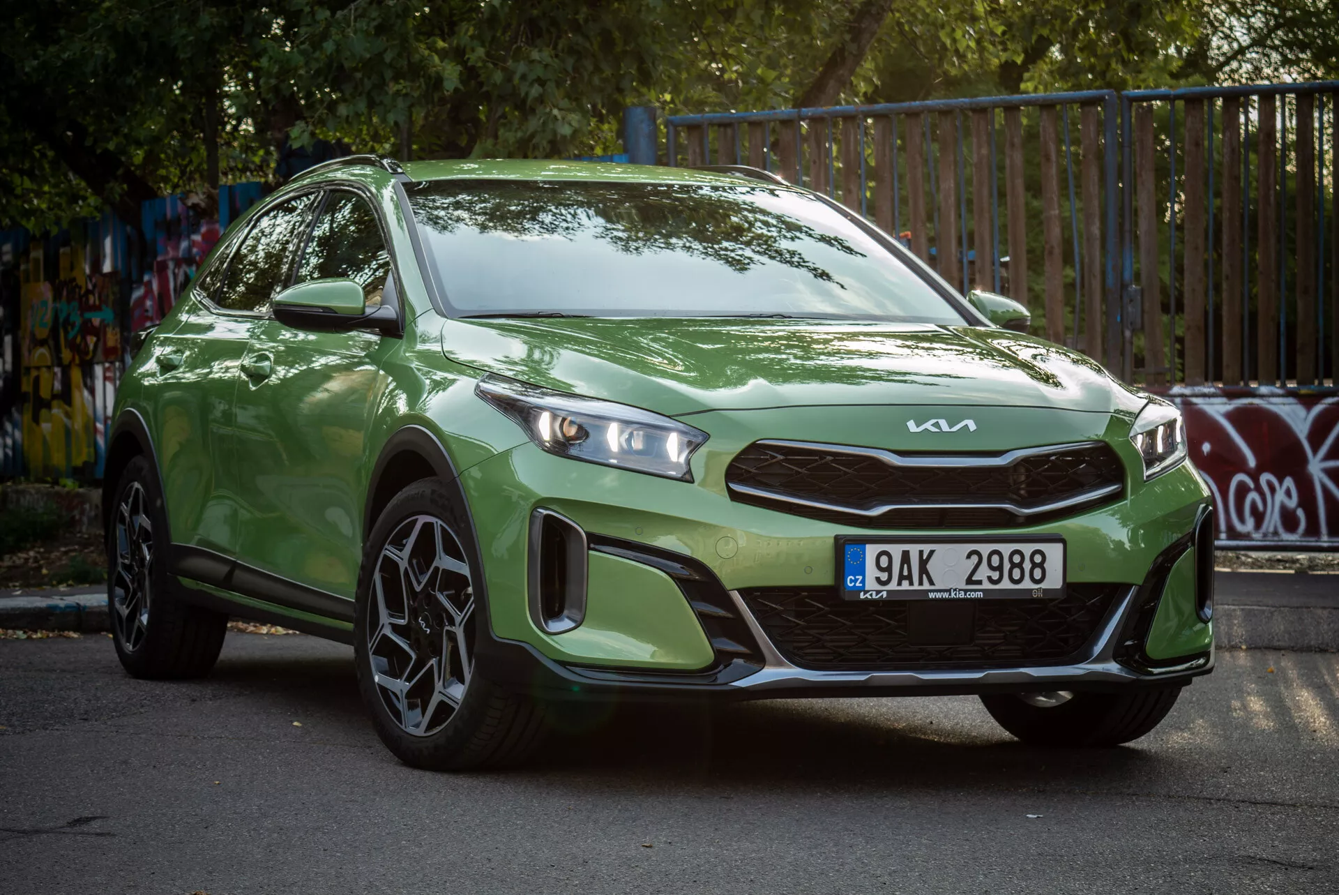 Zelený Kia Xceed 2022 zaparkovaný pod uhlom, predvádzajúci svoj pohľad z prednej časti pod trojštvrtinou s LED svetlometmi a športovými zliatinovými kolesami v mestskom prostredí