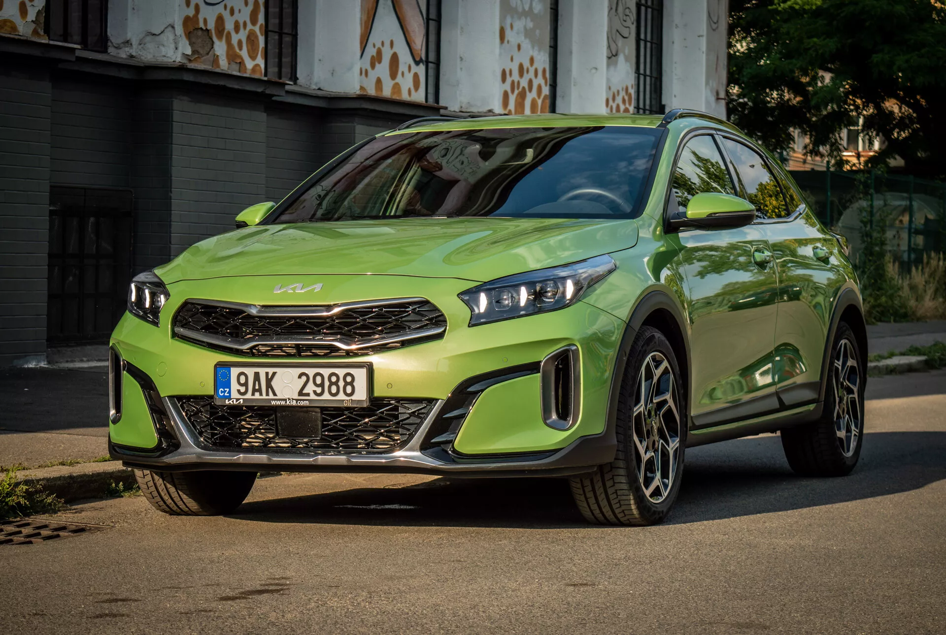 Kia XCeed 2022 v žiarivej limetkovej zelenej s LED svetlometmi, výraznou prednou mriežkou s emblémom značky, športovým predným nárazníkom a veľkými zliatinovými kolesami, umiestnená na spevnenej ceste s mestským pozadím
