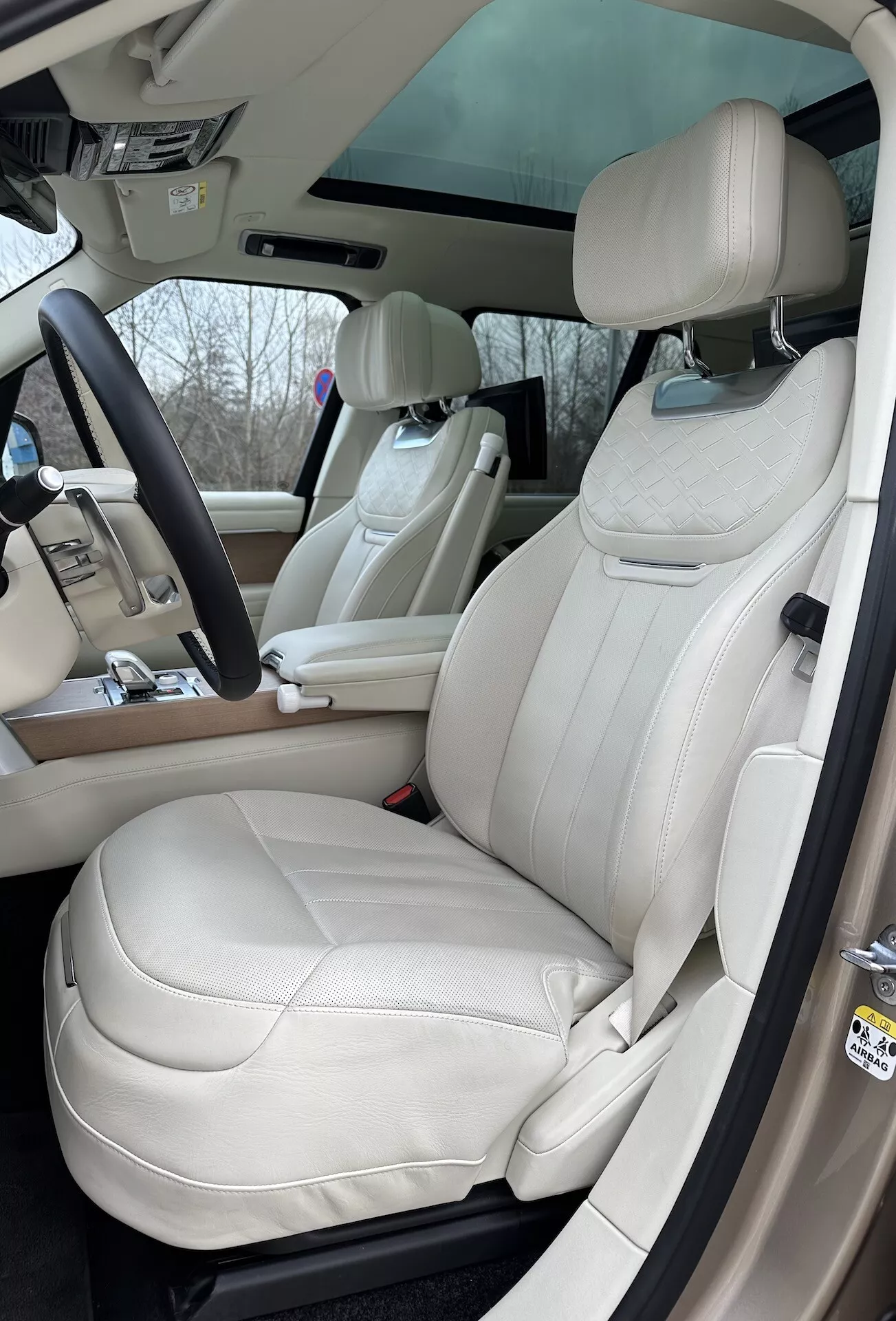 Interiér Land Rover Range Rover 2021 so zameraním na stranu vodiča s luxusnými sedadlami z krémovej kože, multifunkčným volantom a pokročilými ovládacími prvkami na stredovej konzole