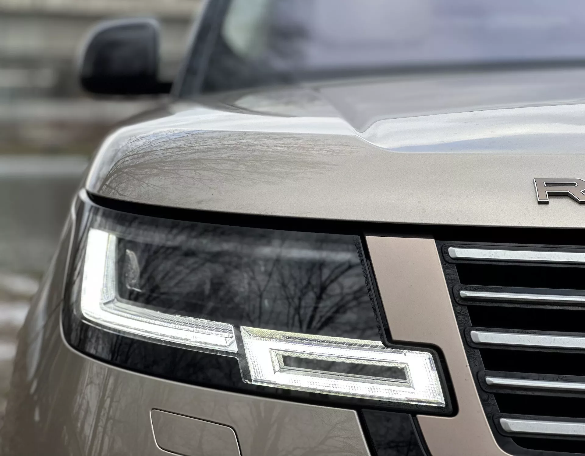 Detailný uhlový pohľad na predný roh Land Rover Range Rover ročník 2021 s LED reflektorom, chrómovou mriežkou a čiastočne viditeľným emblémom na kovovom tele