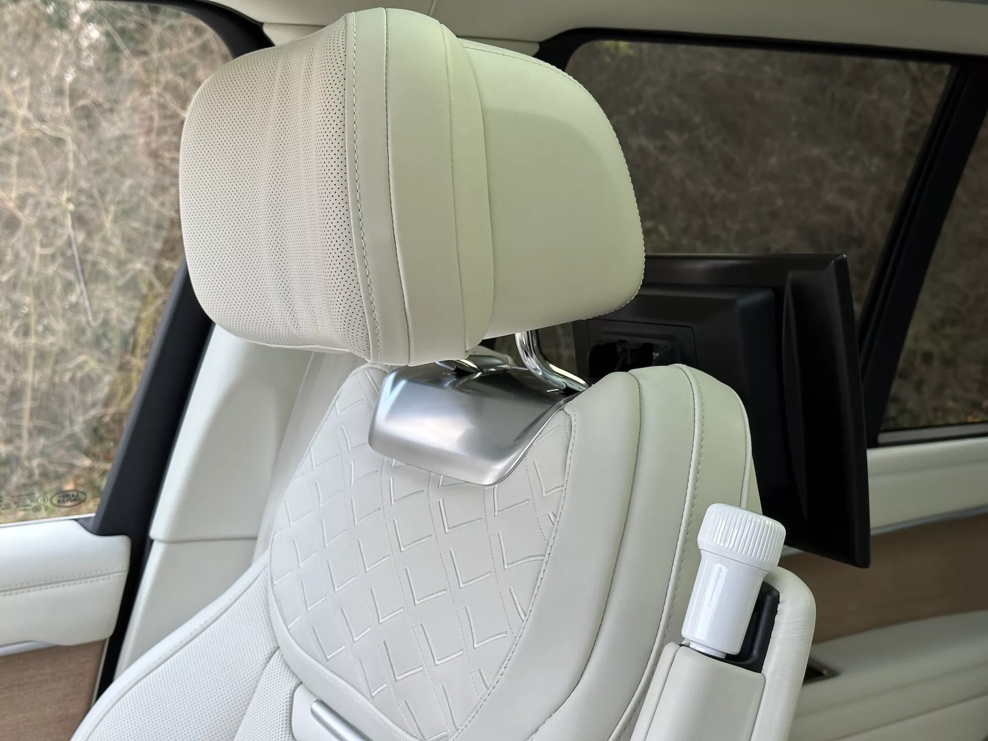Interiér Land Rover Range Rover 2021 s dôrazom na prešívané krémovo-kožené sedadlo spolujazdca s chrómovou opierkou hlavy a držiakom na fľašu na strane dverí, predvádzajúci dizajn luxusných vozidiel a pohodlné funkcie