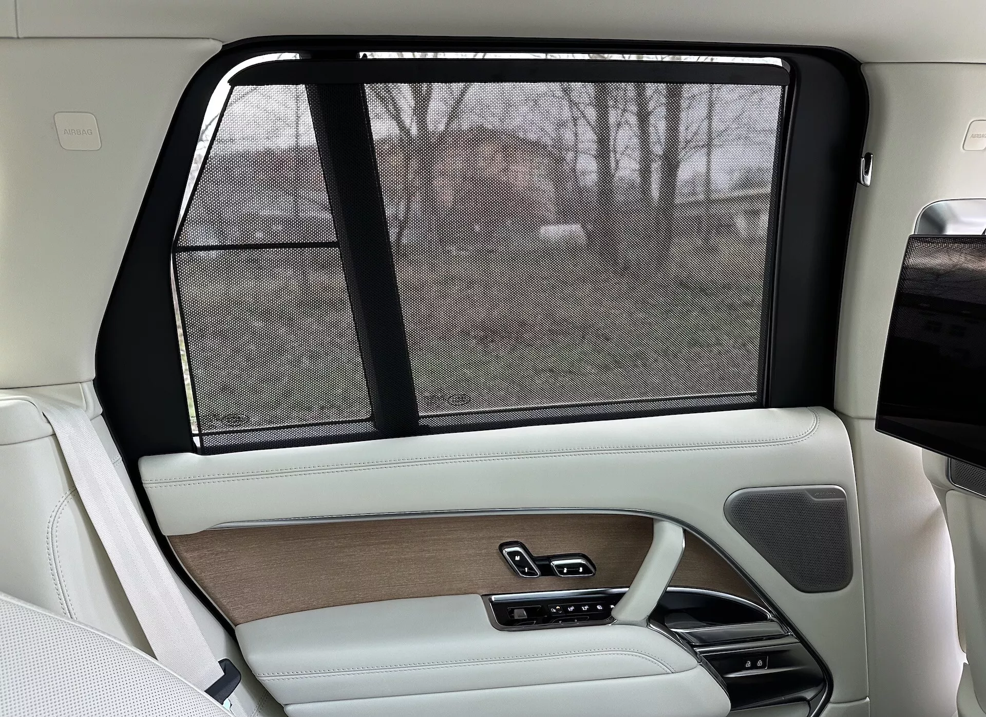 Interiér zadnej pravej strany Land Rover Range Rover 2021, s luxusným dizajnom v béžovej a čiernej farbe, drevodekorami, koženými povrchmi, elektronickou slnečnou clonou a pokročilými ovládacími systémami