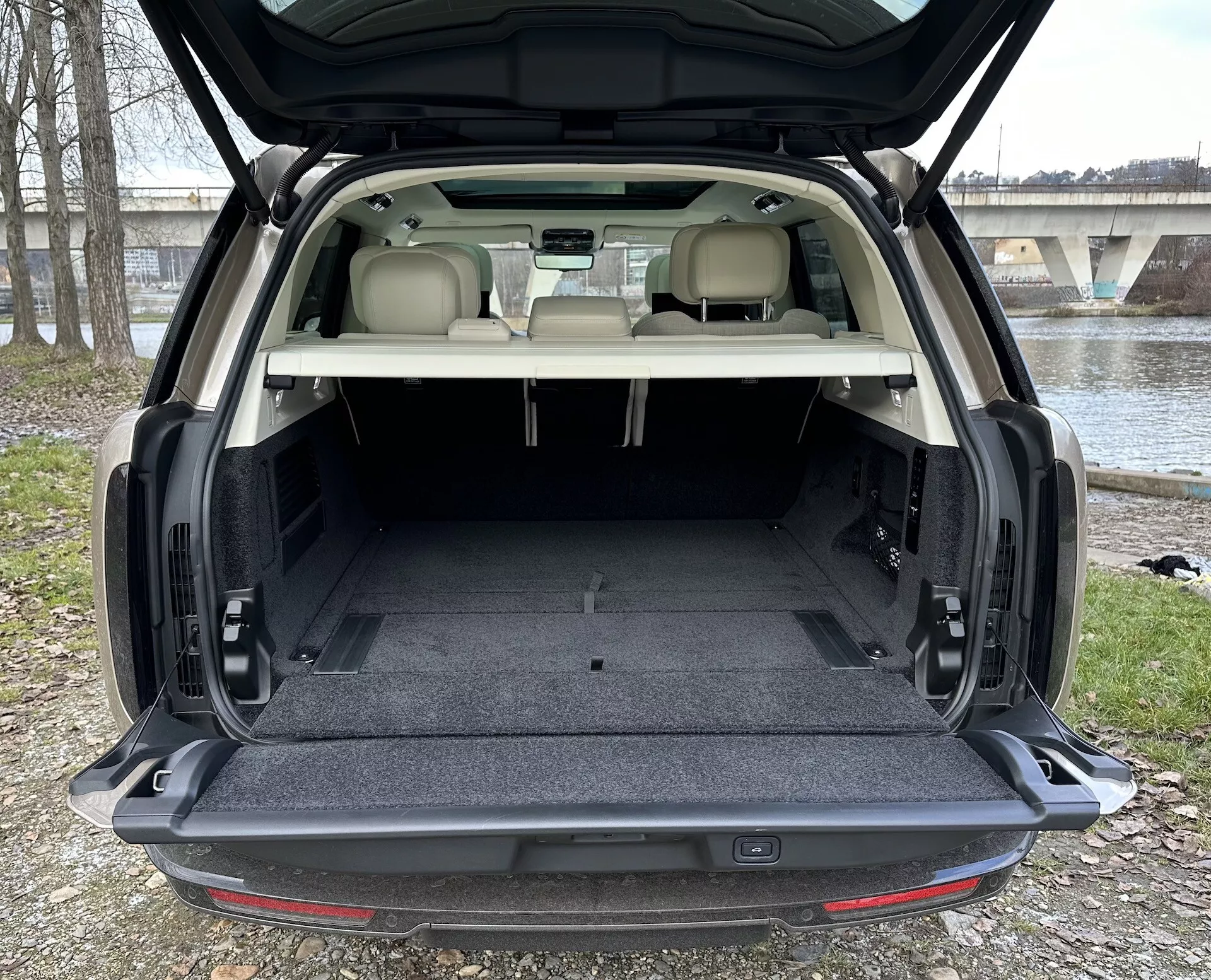 SUV Land Rover Range Rover 2021 ukazuje priestranný zadný nákladový priestor s otvoreným zadným výklopom, čalúnenie svetlej farby v kontraste s tmavým kobercom a vnútorné prvky vrátane osvetlenia nákladového priestoru a možných mechanizmov skladania sedadiel