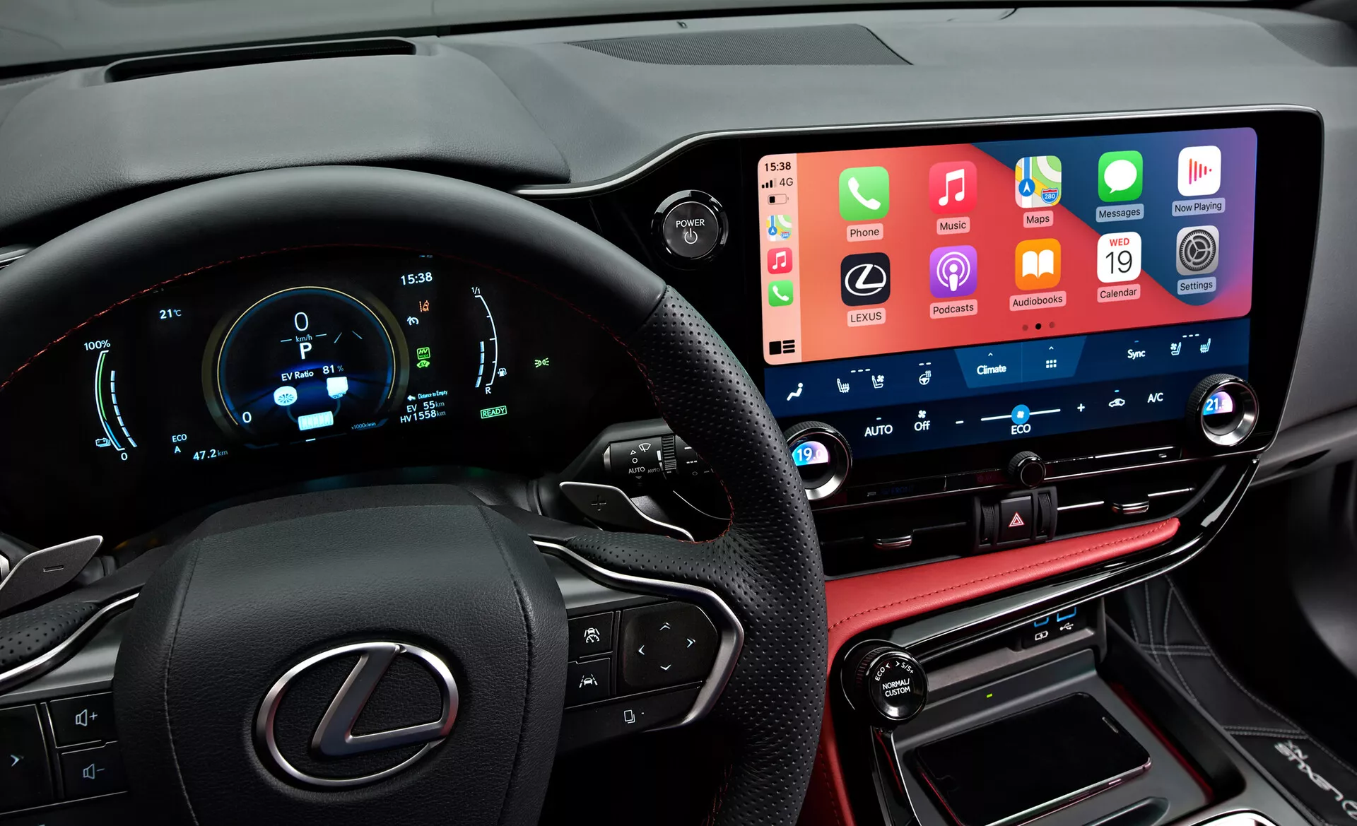 Interiér vozidla Lexus NX 2021 zobrazujúci moderný, technologicky pokročilý prístrojový panel z pohľadu vodiča. Vľavo je čiastočne viditeľný volant s logom Lexus a multifunkčnými tlačidlami. Digitálny prístrojový panel zobrazuje rýchlosť, otáčky a iné metriky v modrej a bielej farbe. Uprostred je široká dotyková obrazovka infotainment systému, ktorá integruje funkcie smartfónov. Pod ňou sú tlačidlá a gombíky klimatizácie s digitálnymi displejmi teploty. Spodná časť obsahuje kožený konzol, radiacu páku a porty na pripojenie, čím odráža luxusné vyhotovenie vozidla.