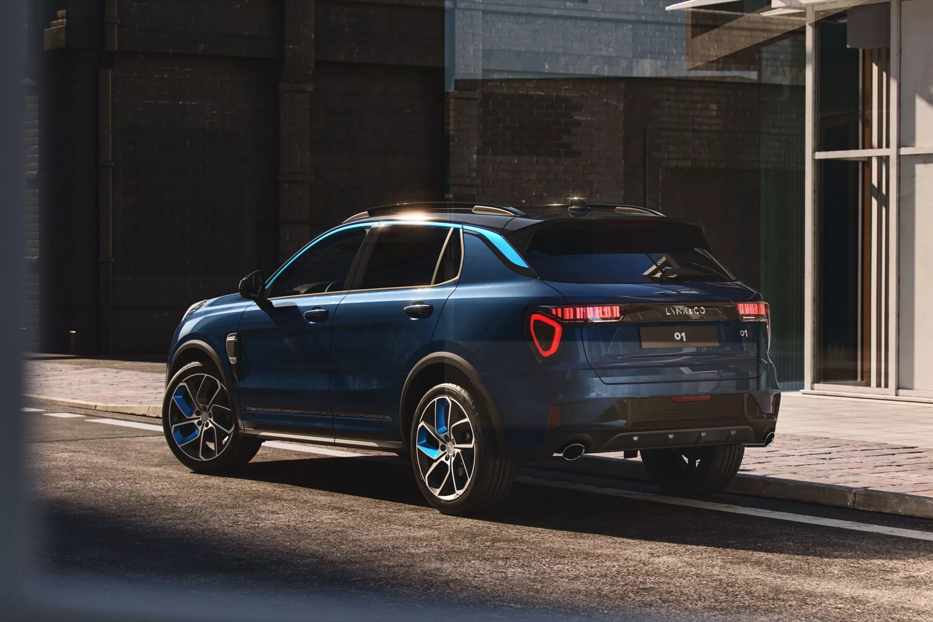 SUV Lynk & Co 01 z roku 2021 v modernom mestskom prostredí, prezentované v prirodzenom slnečnom svetle so záberom z trojštvrte zadnej perspektívy, ktorý zdôrazňuje elegantný dizajn, zadné LED svetlá, dvojitý výfuk, veľké zliatinové kolesá a praktické strešné lyžiny