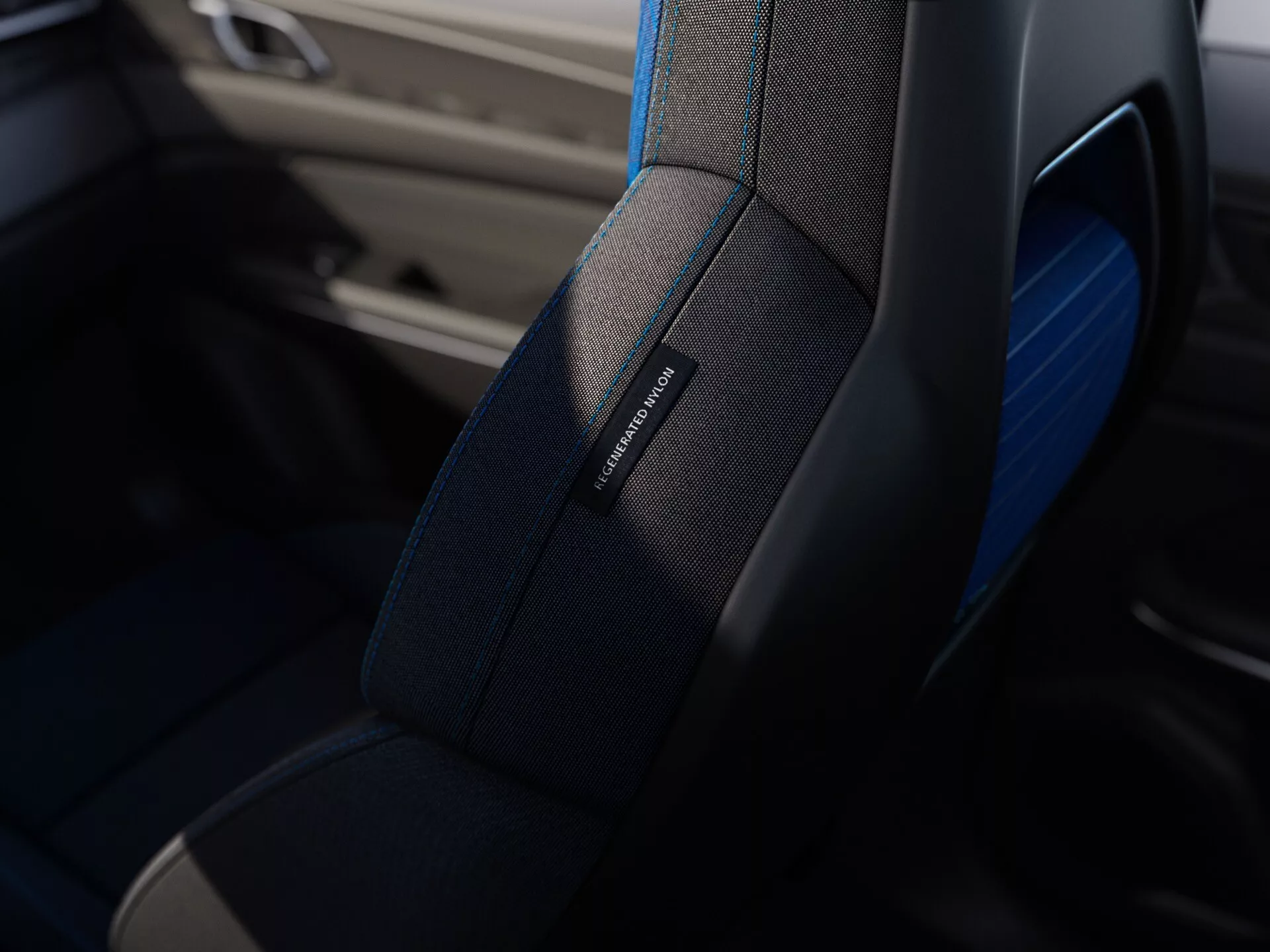 Detailný pohľad na vysoko kvalitné sedadlo automobilu s jemným štepovaním, decentným modrým lemom a označením mena modelu, naznačujúce luxus alebo športovosť, z Lynk & Co 01 2021