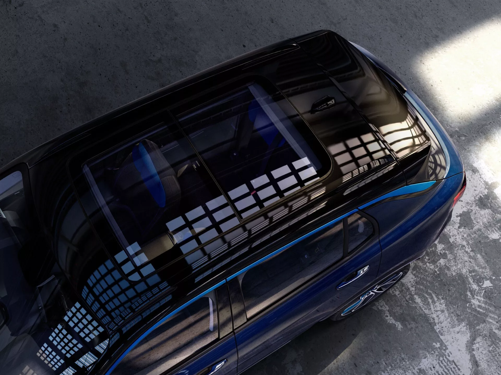 Vysokouhlý letecký pohľad na Lynk & Co 01 z roku 2021 zameraný na zadnú časť, vrátane panoramatickej strechy, elegantnej metalízovanej modrej farby a aerodynamického dizajnu zdôrazňujúce luxus a modernosť.