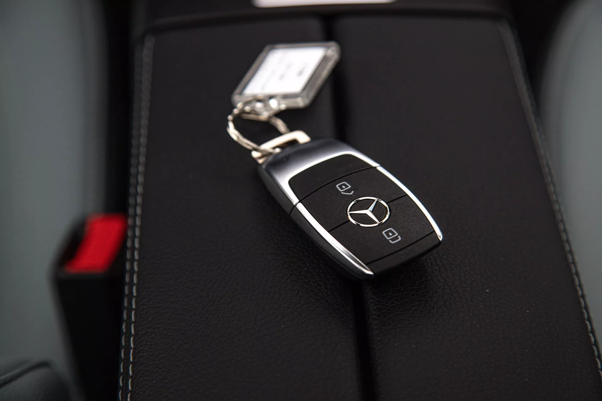 Detailný pohľad na kľúč od Mercedes-Benz triedy A 2022 na koženom sedadle auta s logom a inteligentnými funkciami