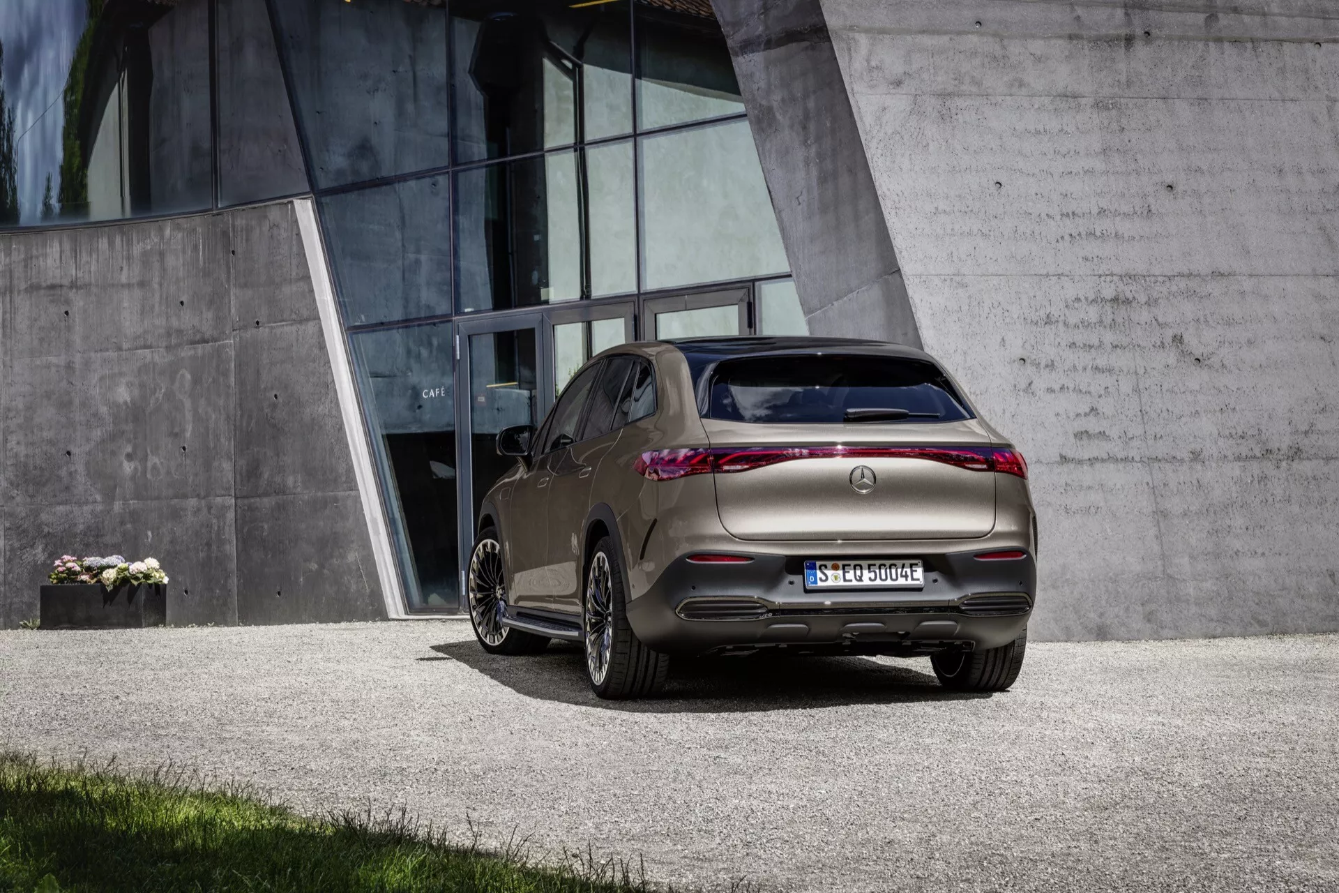 SUV Mercedes-Benz EQE 2023 vyfotografované z uhla tri štvrtiny zozadu, čo zdôrazňuje jeho zadné svetlá, zadný nárazník, časť zadného skla, zadné dvere pre cestujúcich, zadné kolesá, zvýšenú svetlú výšku a tvar karosérie, čo naznačuje moderný crossoverový SUV dizajn, s viditeľnými zliatinovými kolesami a umiestnené proti súčasnému mestskému pozadiu.