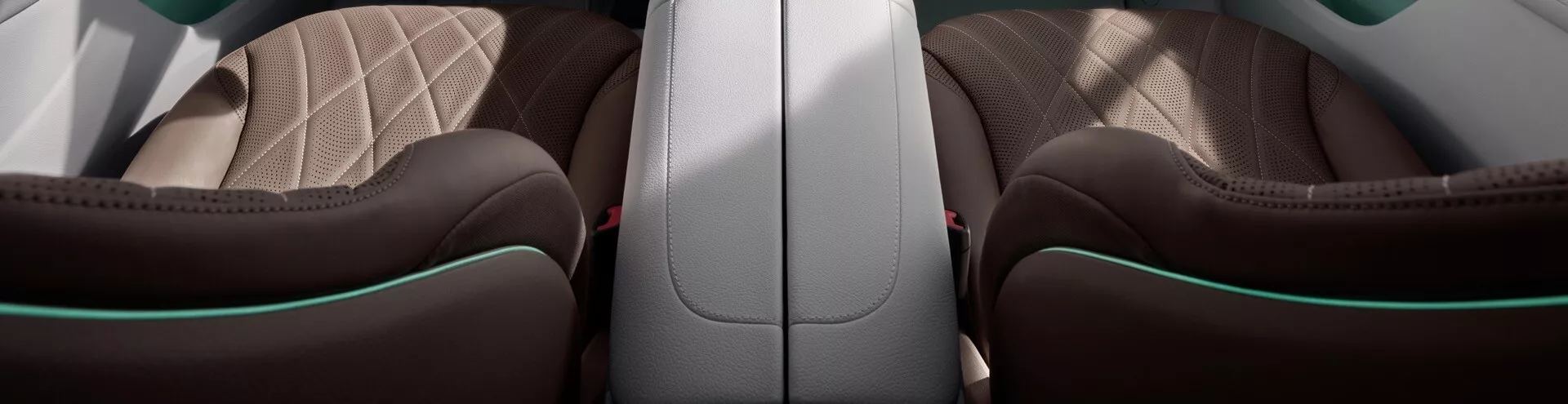 Interiér Mercedes-Benz EQE-SUV 2023 s luxusne vybaveným zadným cestujúcim priestorom s opierkou z šedej alebo bielej kože, čierne alebo hlboko hnedé sedadlá s diamantovým prešívaním a unikátnym zeleným lemovaním, zdôrazňujúci remeselnú kvalitu a komfortné funkcie.