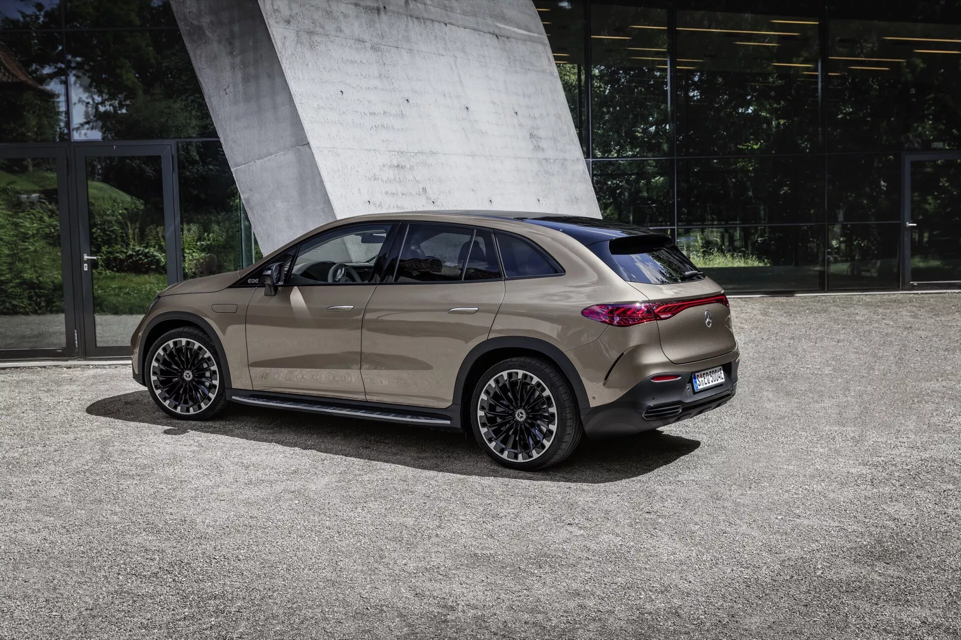 Zadný bočný pohľad na Mercedes-Benz EQE SUV 2023 ukazujúci jeho elegantný dizajn, metalický lak, zliatinové kolesá s viacerými lúčmi a LED zadné svetlá proti sofistikovanému vonkajšiemu prostrediu