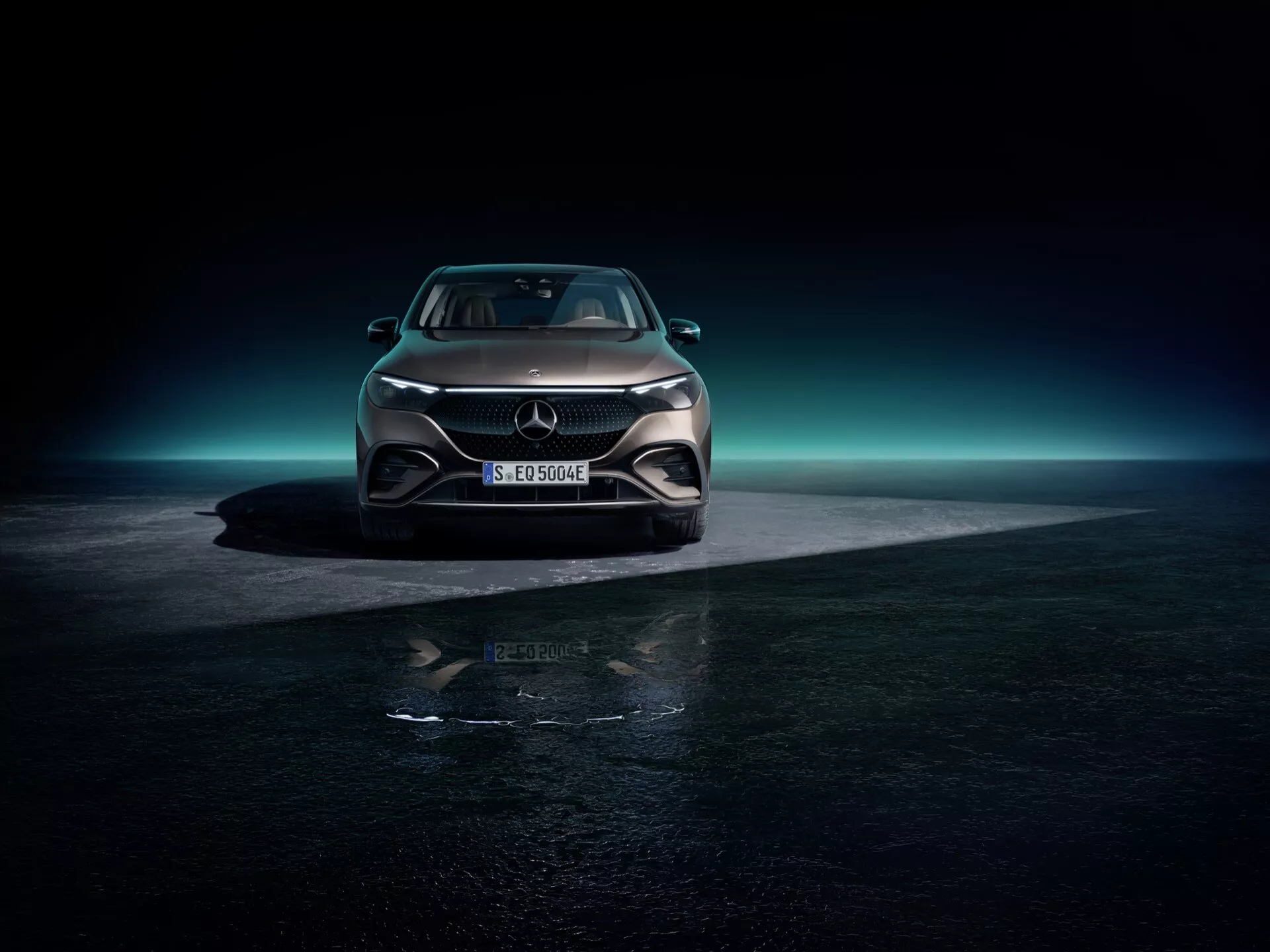 Mercedes-Benz EQE-SUV 2023 fotografované z nízkeho uhla z prednej strany s dôrazom na ľavú stranu vozidla, zobrazujúce celú prednú časť vrátane mriežky, LED svetlometov a aerodynamického nárazníka na tmavom pozadí s modrastým ambientným osvetlením