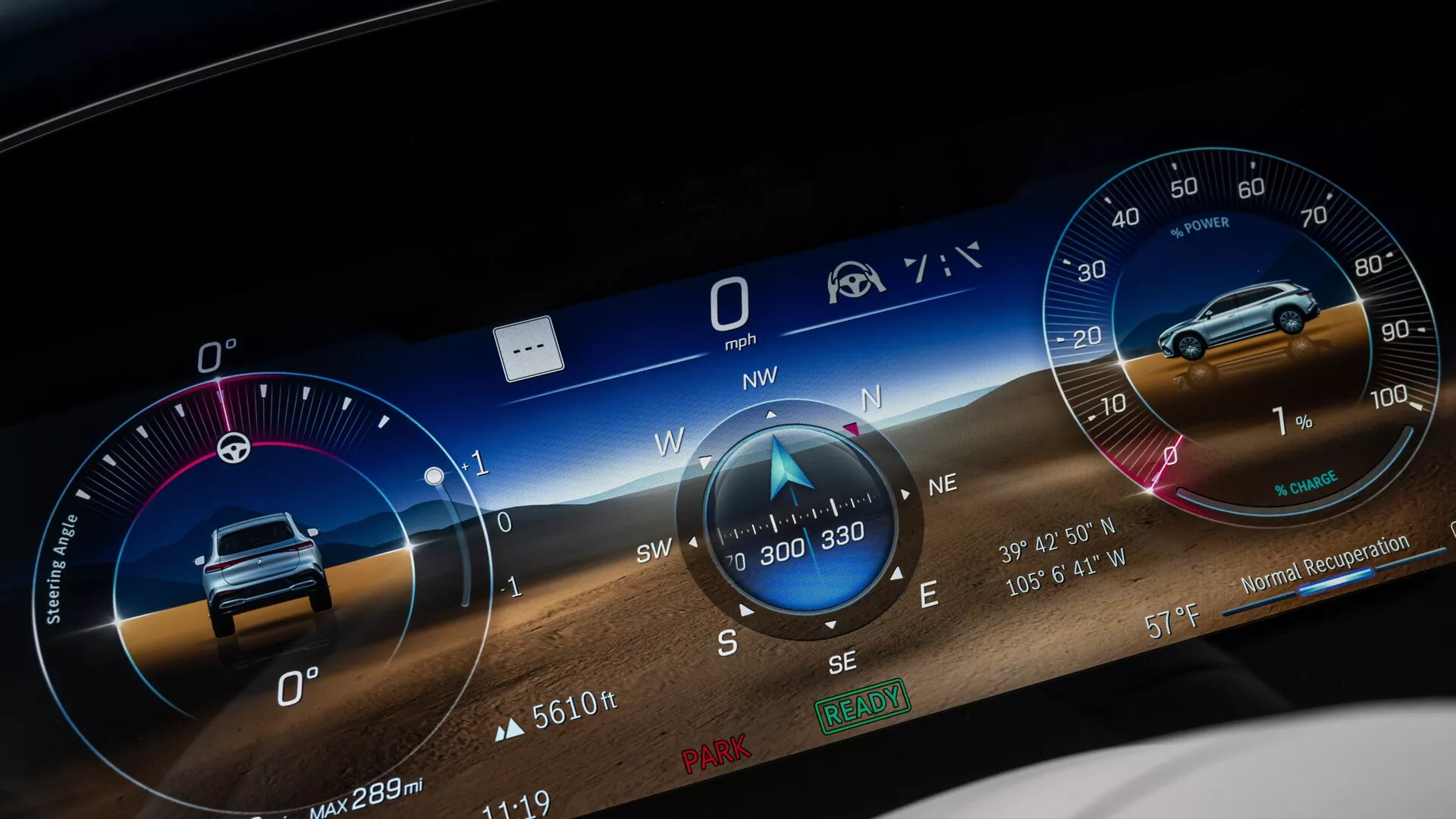 Detailný záber na digitálny prístrojový panel Mercedes EQS SUV 2022, obsahujúci širokouhlé grafické užívateľské rozhranie zobrazujúce rôzne metriky, ako je rýchlomer na 0 mph, kompas ukazujúci na severozápad, pravdepodobne otáčkomer, informácie o najazdených kilometroch, napríklad 'Max 289m,' a ikony pripomienkovača bezpečnostného pásu a asistencie vodiča. Pozadie obsahuje dynamickú krajinu pre vizuálnu príťažlivosť.