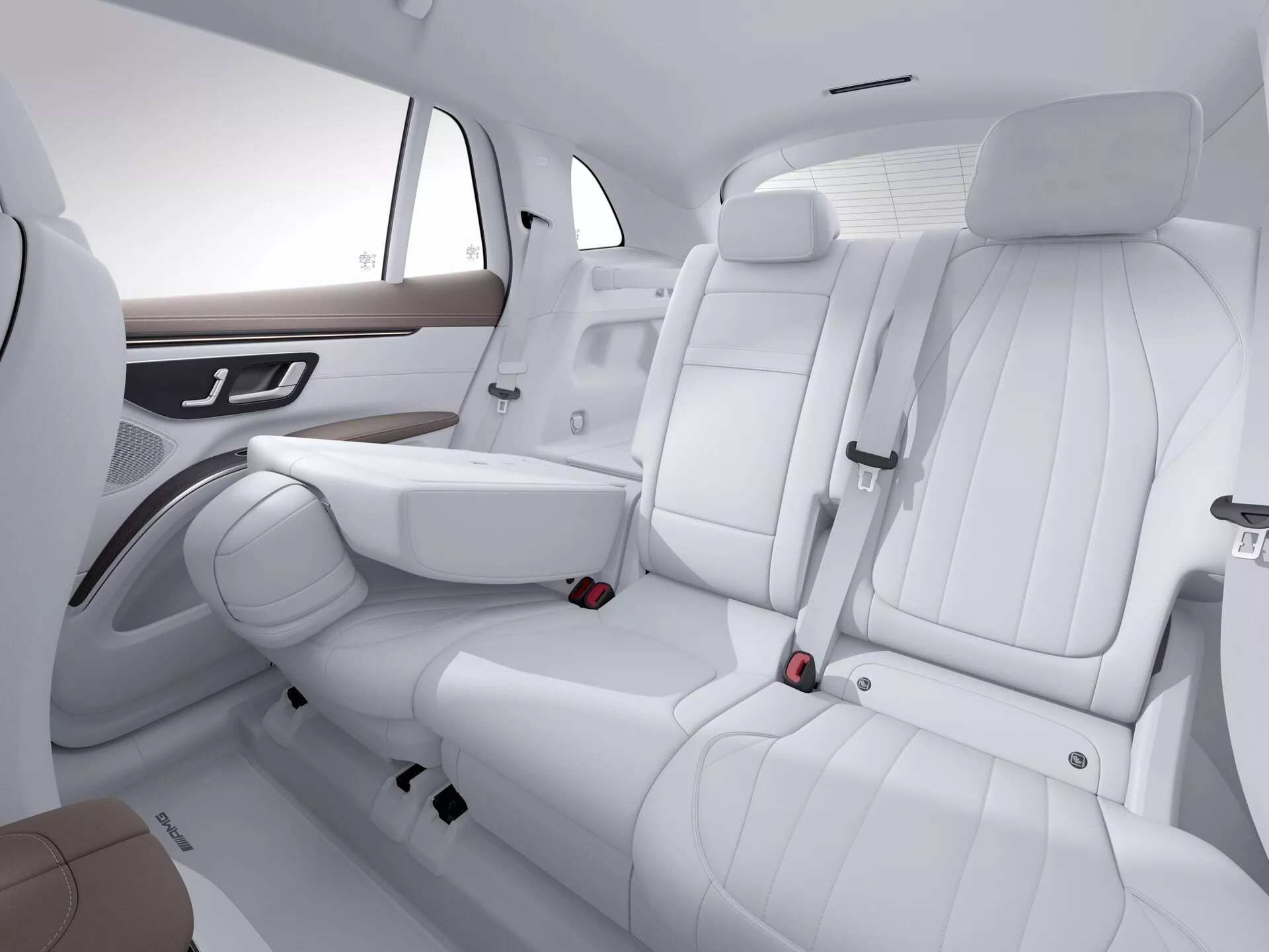 Interiér Mercedes EQS SUV 2022 so zameraním na zadné sedadlá z predno-pravej perspektívy. Tri sedadlá z bielej kože s detailným prešívaním majú v strednom sedadle sklápateľnú lakťovú opierku. Integrované opierky hlavy a trojbodové bezpečnostné pásy zaisťujú bezpečnosť, zatiaľ čo drevené dekory a chrómové kľučky na bočných opierkach zdôrazňujú luxus. Minimalistický dizajn dverových panelov a priestranný layout zvyšujú čistú estetiku. Štúdiové nastavenie zvýrazňuje moderný, čistý a vysoko kvalitný interiér auta.