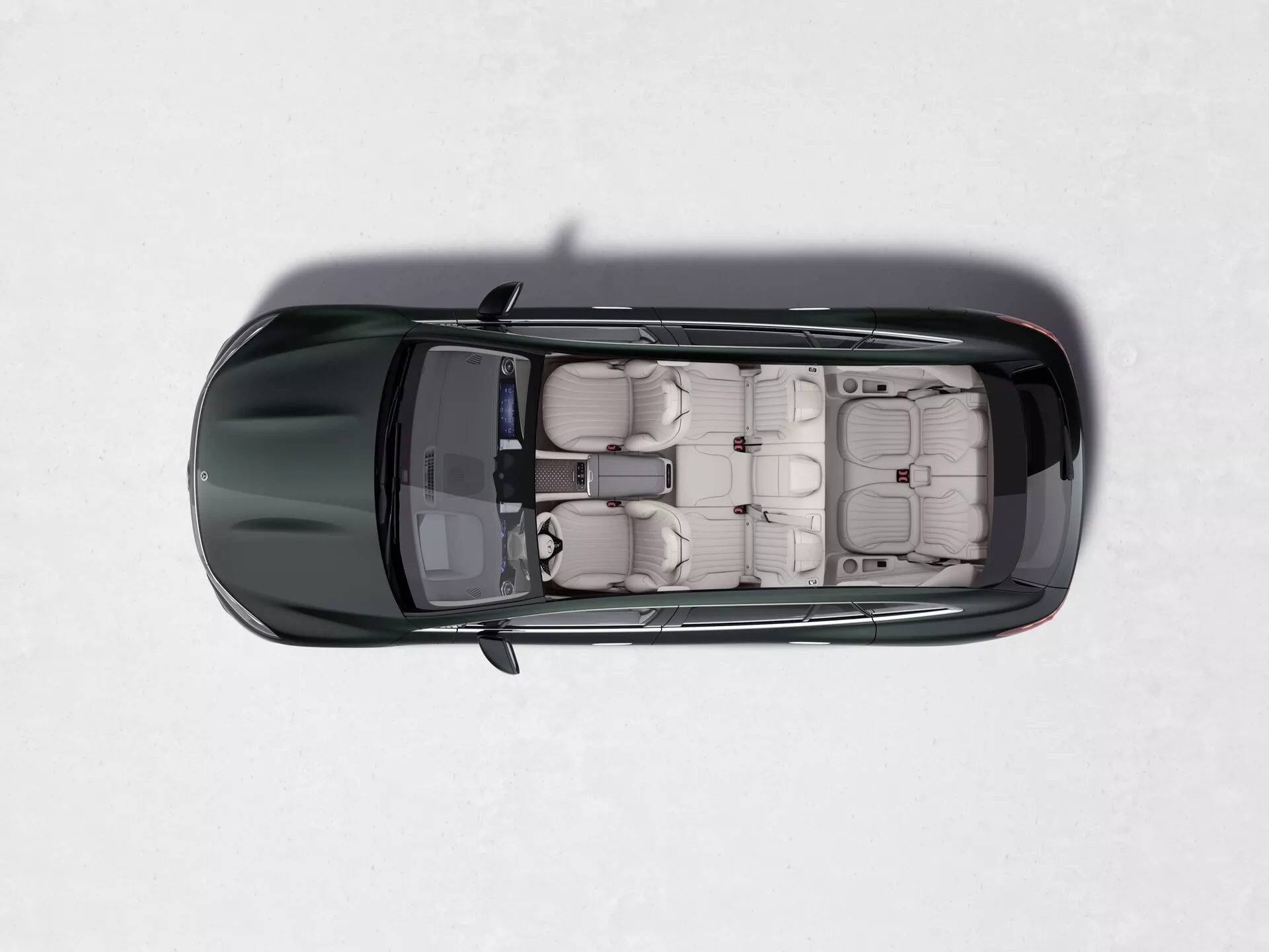 Pohľad zhora na Mercedes EQS SUV 2022, ktorý ukazuje jeho strešné okno, svetlé kožené čalúnenie, samostatné sedadlá s opierkami hlavy, štyri dvere so zapustenými kľučkami, lesklý tmavý lak a kontrastné bočné zrkadlá na svetlom, jednotnom pozadí.