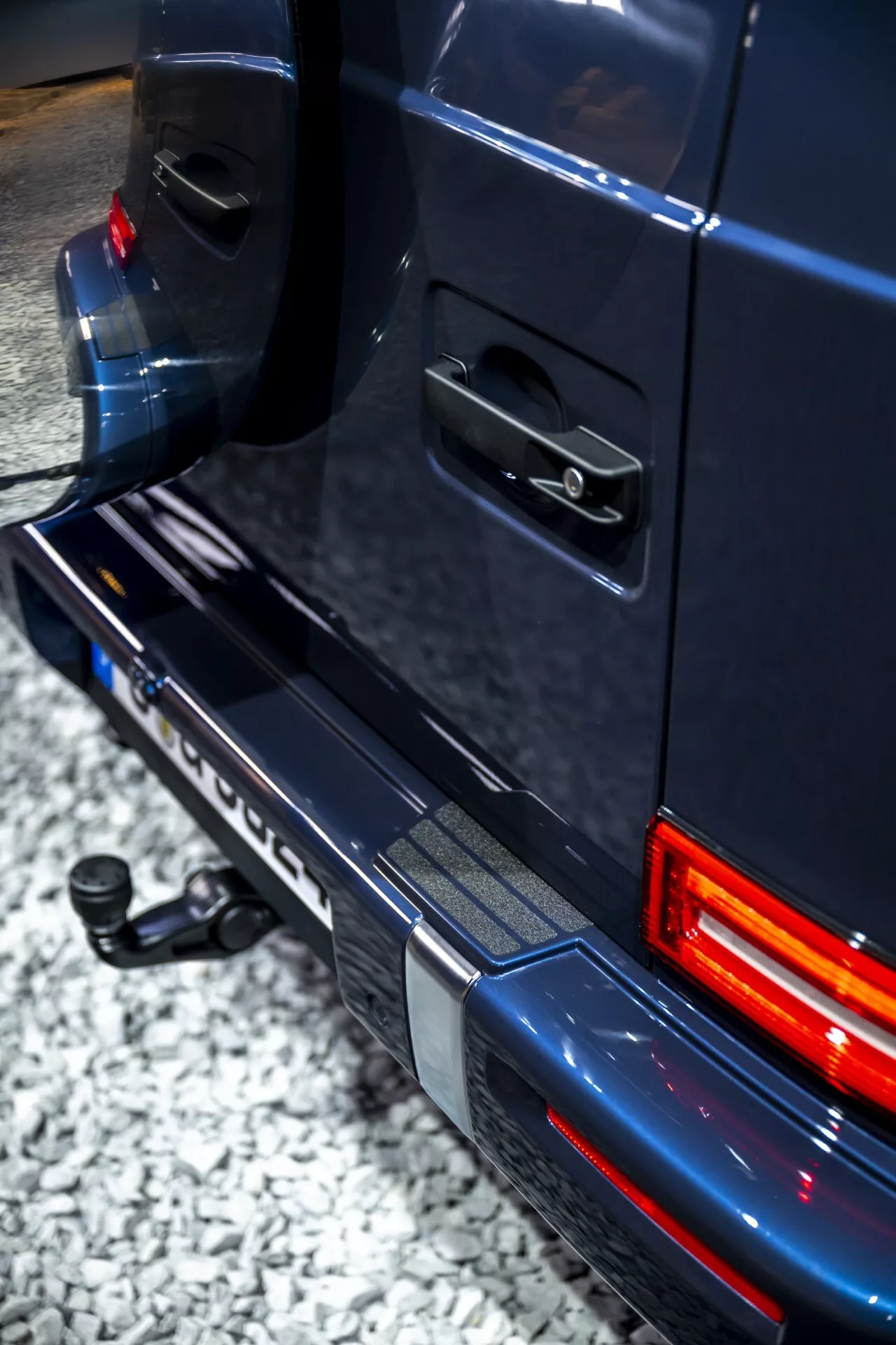 Detailný uhlový pohľad zdôrazňujúci zadnú časť Mercedes-Benz G-Klasse 2024, zobrazujúci detail pravej strany zadného svetla, nárazníka a dverí s LED osvetlením a prvkami na ťahanie.