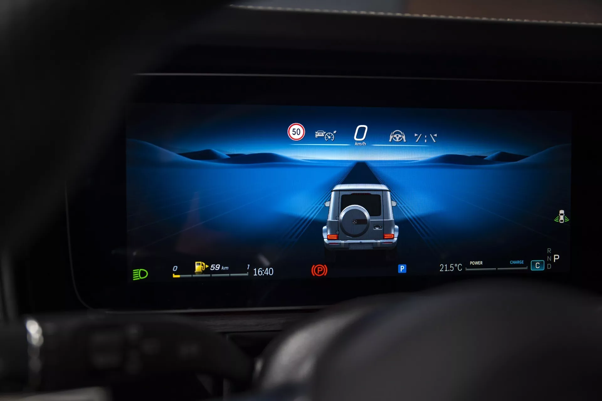 Displej digitálneho palubného počítača Mercedes-Benz G-Klasse 2024 zobrazujúci pomoc pri parkovaní s 360 stupňovým výhľadom s aktívnymi bezpečnostnými funkciami a indikátormi elektrického pohonu