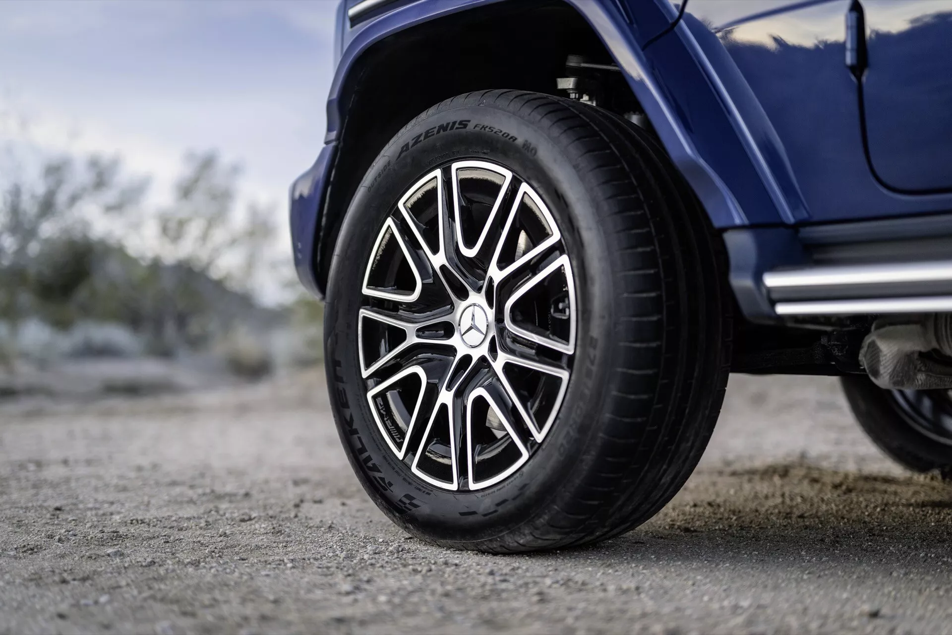 Detailný pohľad na pravé koleso Mercedes-Benz G-Klasse 2024 s pneumatikou Michelin a športovým dizajnom ráfika na pozadí vonkajšieho prostredia