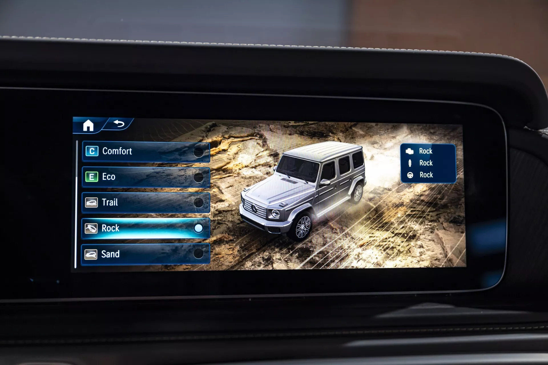 Záber na digitálny displej vo vnútri Mercedes-Benz triedy G 2024 zobrazujúci 3D model SUV v terénnom prostredí s možnosťami terénnych režimov na obrazovke