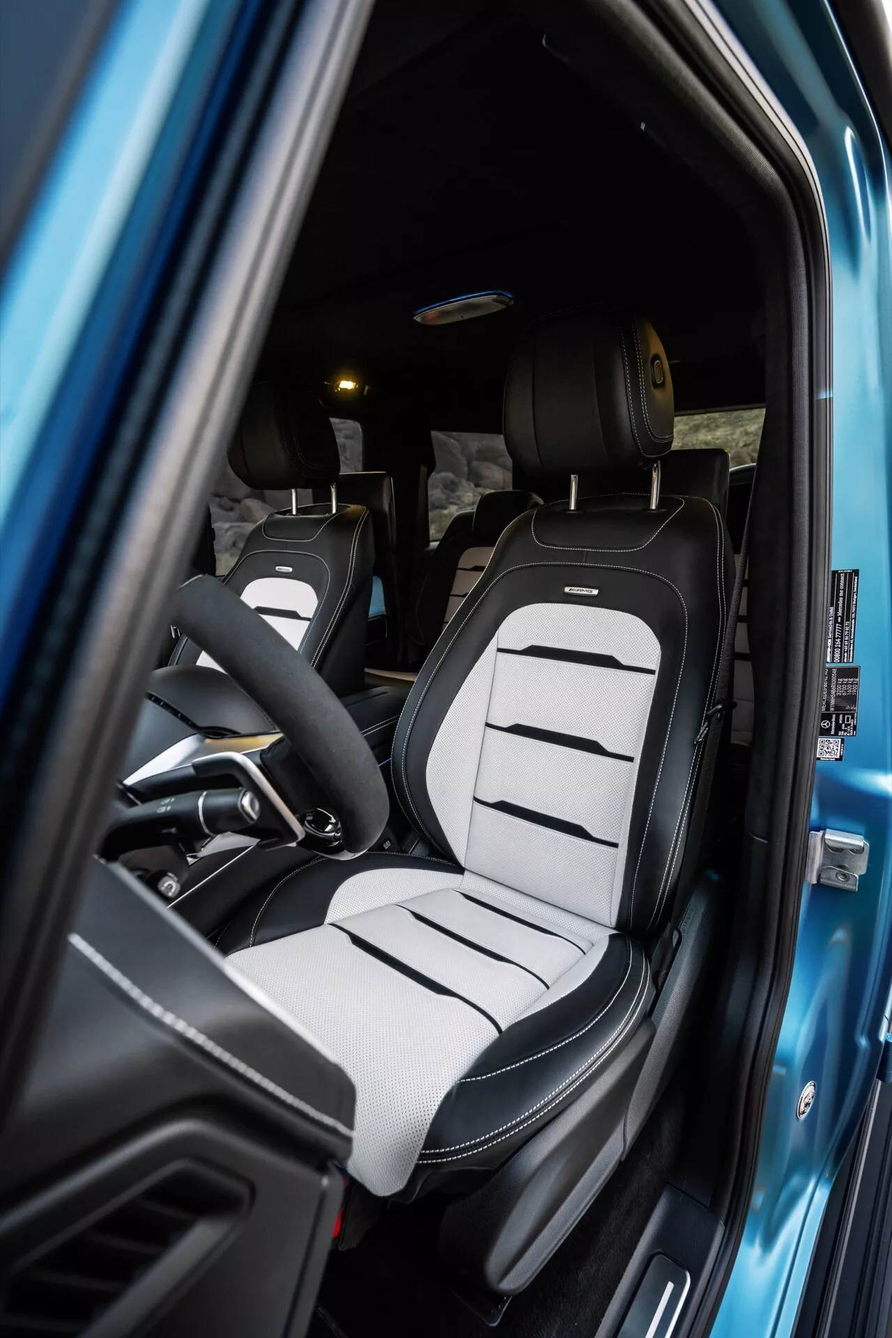 Interiér Mercedes-Benz G-Klasse (465) pre rok 2024 so zameraním na sedadlo vodiča s dvojfarebným čalúnením a moderným dizajnom sedadla typu bucket cez otvorené dvere