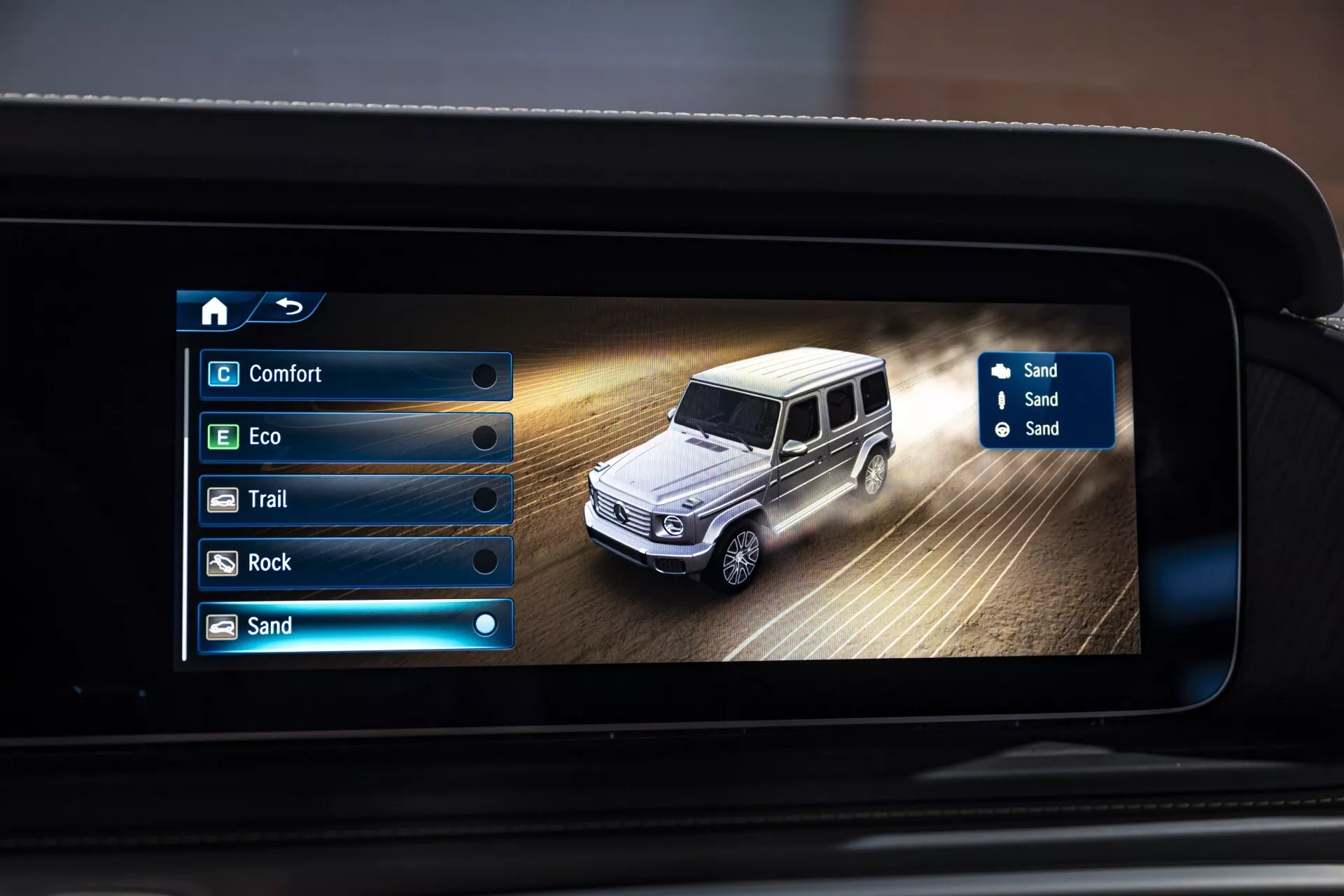 Displej informačného systému Mercedes-Benz G-Klasse 2024 zobrazujúci režim jazdy v piesku s digitálnym zobrazením auta